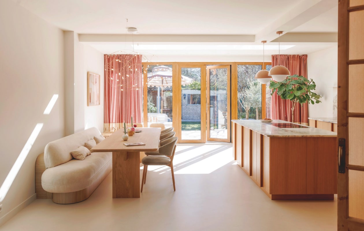 Stoelen in stof Guard Eucalyptus 193 en tafel Table du Sud. Bank, kussens Studio Diezijn. Kandelaars Leen Bakker. Hanglampen en vaasje Westwing. Maatwerkkeuken Reform. Keukenblad Jan Reek natuursteen. Gordijnen zelfgemaakt. Stone Age vloer Beton Ciré crème- grit. Muurverf Overtoom uit Interieurvanmies-kleurencollectie van Fairf. Schuifpui eigen ontwerp. vtwonen 7-2025 | fotografie Emma Peijnenburg