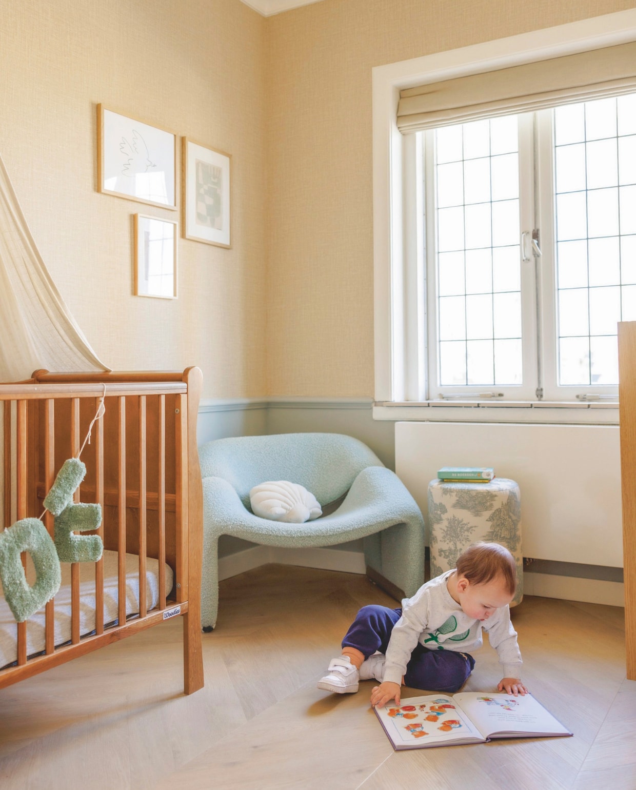 Kinderbed Hola BB. Letterslinger Betuft. Fauteuil Artifort Groovy gestoffeerd door Studio Diezijn. Schelpenkussen Westwing. Poef Amstelièr. Kunstwerken cadeau gekregen. Vloer Belakos Palazzo 74. Muurverf Bastille van Fairf. Raambekleding Veneta. vtwonen 7-2025 | fotografie Emma Peijnenburg