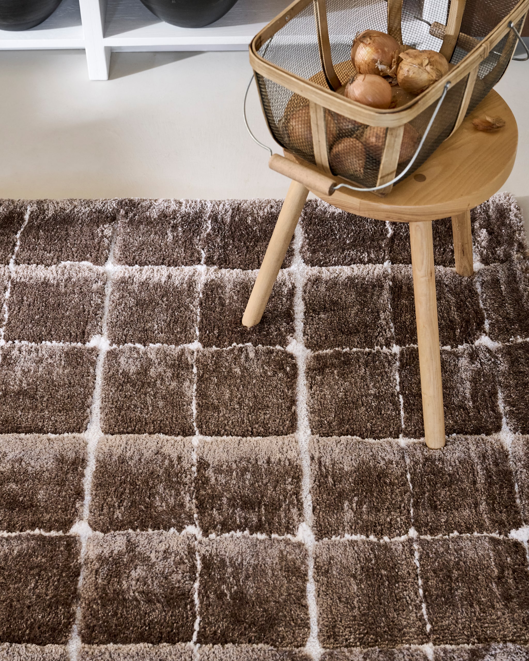 vtwonen vloerkleed Blocks, gerecycled polyester en jute, warm brown, vanaf 80x240 cm € 239,-.M.m.v. dille-kamille.nl (stoel, houten schalen, tadelakt schaal, rieten tas, tafel), householdhardware.nl (glaswerk, linnen doek, oogstmand, kruk), letoile.store (zeepdispenser). vtwonen 10-2025 | styling Sanne Ketelaar, Marlies Does | fotografie Sjoerd Eickmans, Peggy Janssen