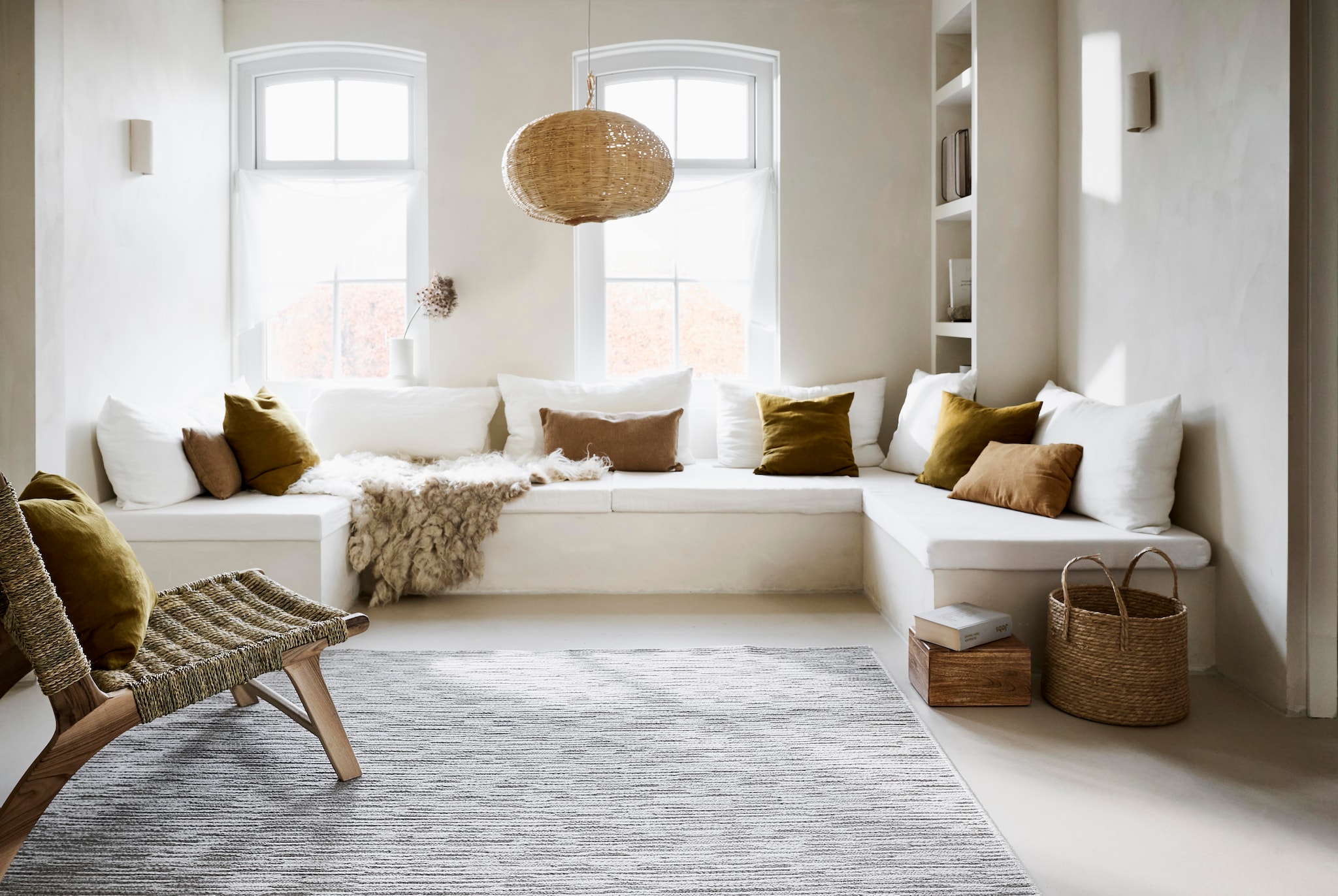 vtwonen vloerkleed Nature Cord, 100% kwaliteitswol, grijs melé, 160x230 cm € 449,-, 200x290 cm € 719,- en 240x330 cm € 975,-.M.m.v. householdhardware.nl (lamp, mand), urbannatureculture.com (houten kistje, kussens), casagitane.com (lantaarn). vtwonen 10-2025 | styling Sanne Ketelaar, Marlies Does | fotografie Sjoerd Eickmans, Peggy Janssen