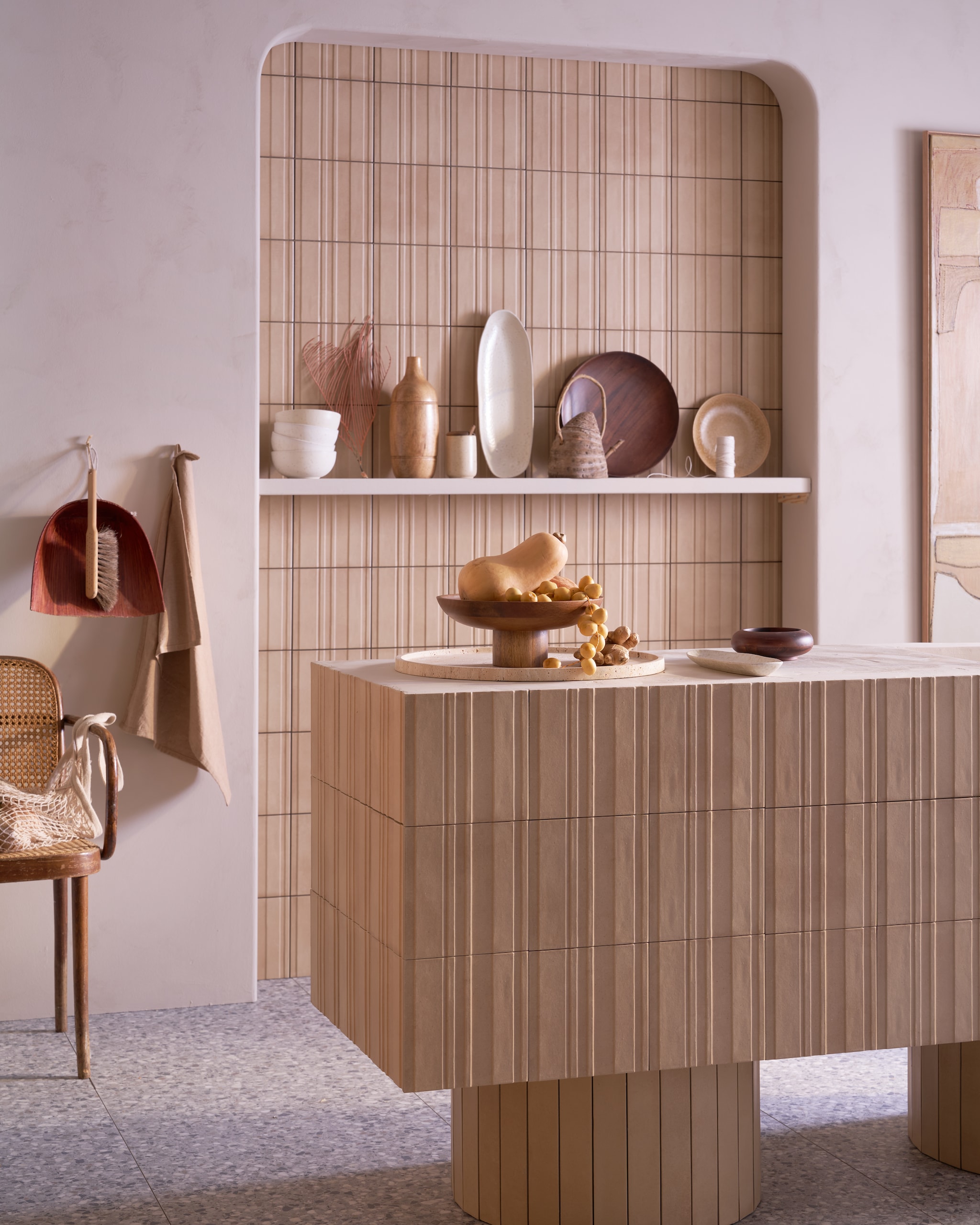 Op de vloer tegels Terrazzo Smoke Flakes, 60x120 cm, per m² € 74,50. Op keukenblok en achterwand tegels Earth Calce 3D Decor, 20x20 cm, per m² € 64,50. Op pilaar en keukenblokpoten tegels Earth Calce, 5x30 cm, per m² € 79,50.M.m.v. vestingh.nl (kalkverf Mushroom van Lab Paint), ilsevanstoltz.com (schilderij), vtwonen.nl/shop (kruk Pawn van Serax, kommen en bruin bord van vtwonen), hm.com (schaal op voet, houten dienblad, ovale schaal, suikerpot). Overig privébezit. vtwonen 09-2024 | styling Cleo Scheulderman | fotografie Jeroen van der Spek