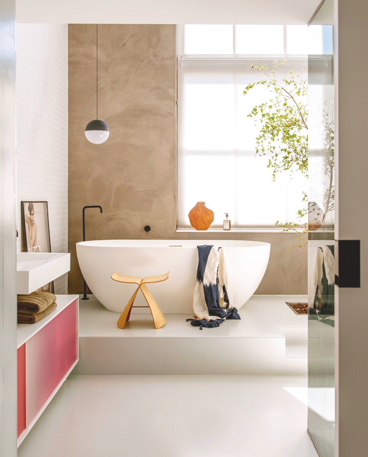 Butterfly Stool van Sori Yanagi van Vitra. Dressoir Shift van Scholten & Baijings voor Pastoe.  Hanglamp String Light Sphere van Michael Anastassiades voor Flos. Vaas Willem van Hooff. Bad Solid Surface via X2O. Wandtegels Villeroy & Boch. Boom Bucida buceras. stijlvol wonen 7-2025 | styling Anke Helmich | fotografie Caroline Coehorst