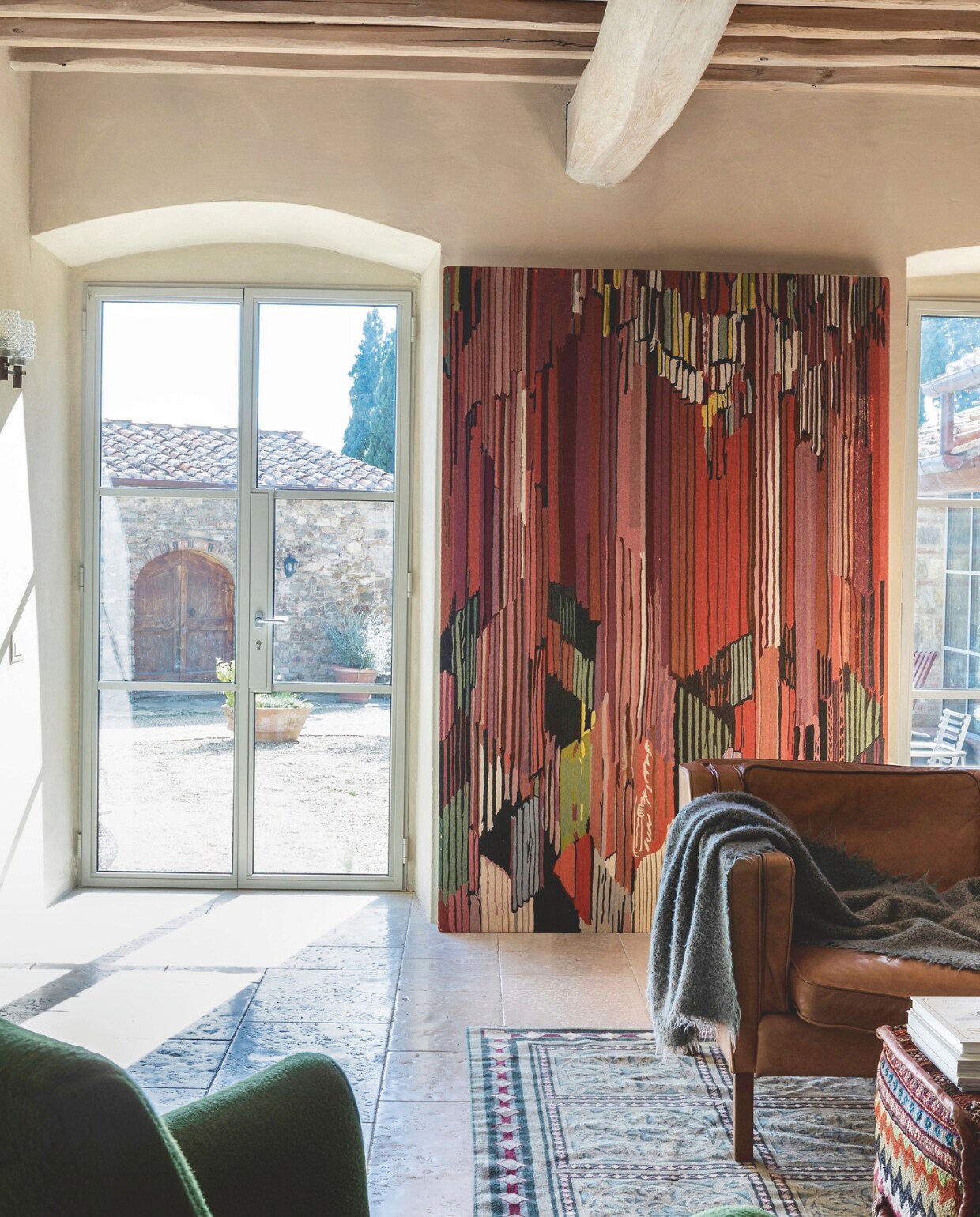 Het wandtapijt is een reproductie van een kunstwerk van František Kupka door Elio Palmisano, via Arredamenti Santiccioli (santiccioli.com). Het is een van de weinige wanddecoraties in het huis. vtwonen landelijk 7-2025 | productie Living Inside | fotografie Monica Spezia