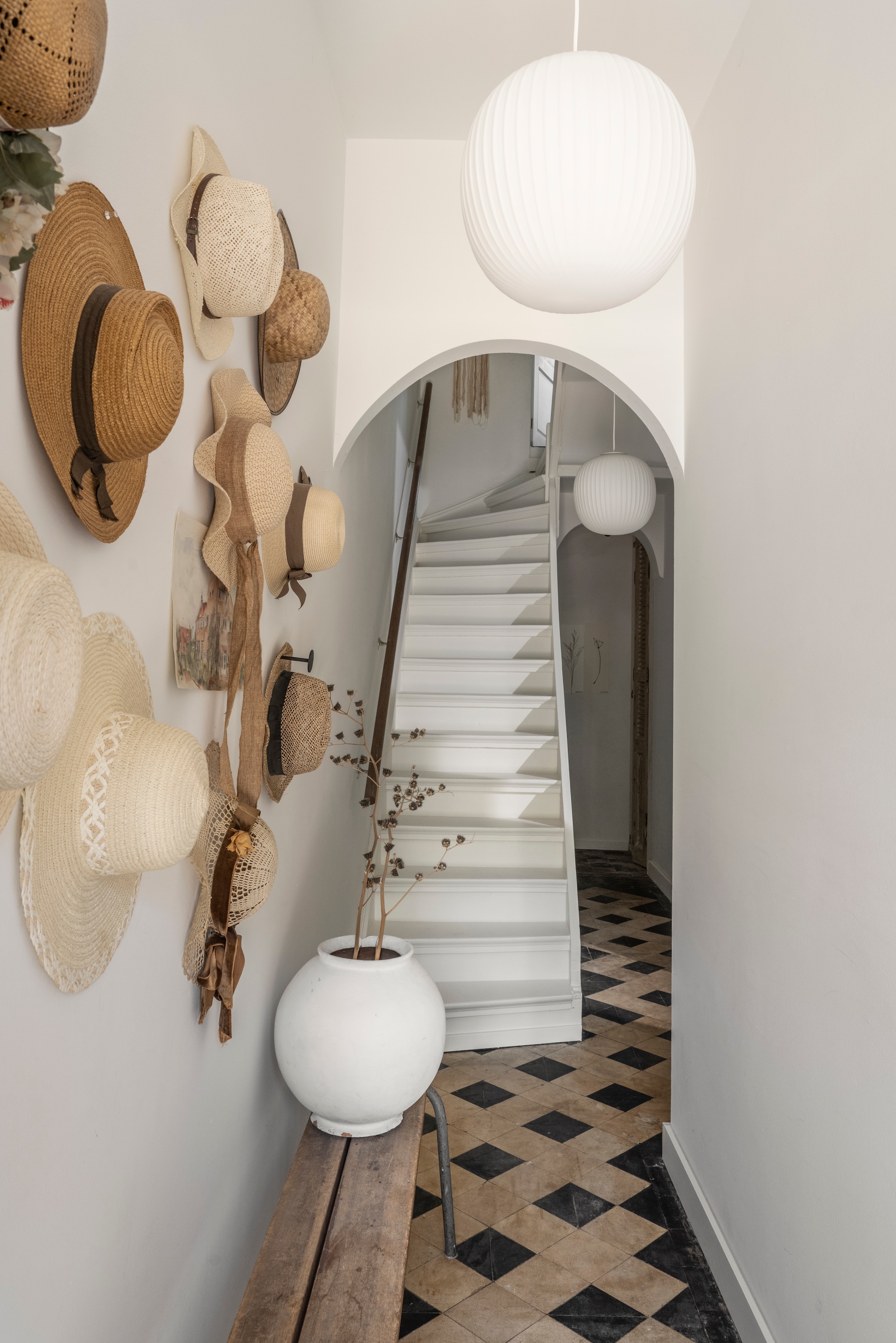 Aan de wand verzamelinghoeden van Jolies moeder. De boogvorm en vloer zijn originele artdeco-elementen. Lampen en traplak Karwei. Witte vaas en gymbank brocante. vtwonen Landelijk 10-2025 | styling Marianne Luning | fotografie Stan Koolen