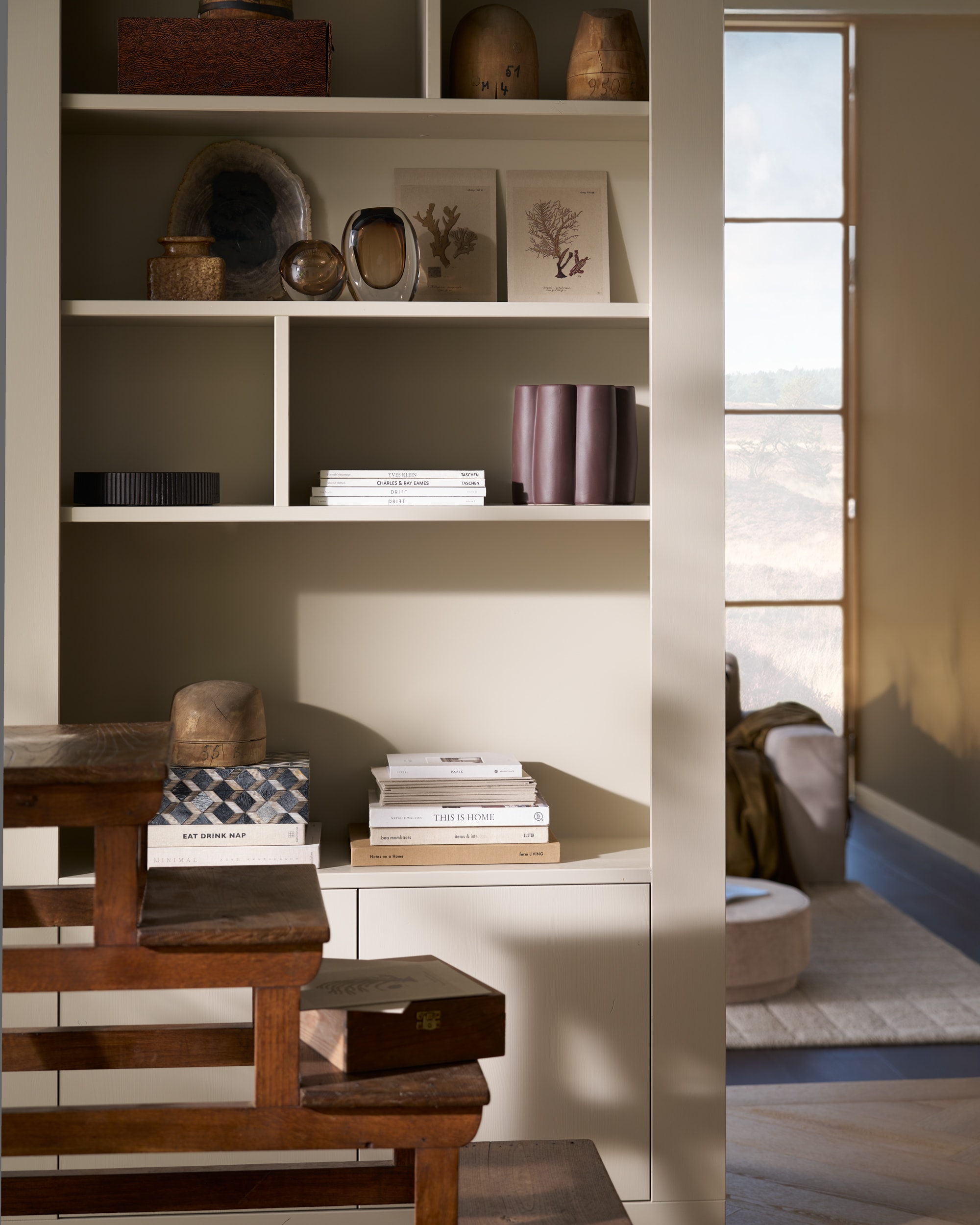 vtwonen wandkast Wallcover, grenen, dust, 117x31x229 cm (bxdxh), per stuk € 799,-, vtwonen poef Pearl en poef Pearl XL, melange stof, naturel, 40x45 cm (Øxh) € 199,- en 80x28 cm (Øxh)€ 199,-, vtwonen salontafel Coffee A Gogo, mangohout, walnoot, 90x40 cm (Øxh) € 499,- en vtwonen 2,5-zitselementenbank Family, geweven stof, zand, 298x98x85 cm (bxdxh) € 1999,-.M.m.v. pietjonker.nl (bibliotheektrap, bijzettafel), hm.com (grafisch kussen), weldaad.com (servies, opbergmand, linnen kussens), burbriantiek.nl (kruiken), vtwonen.nl (visgraat laminaat Rafter, vloerkleed Blocks). Overig privébezit. vtwonen 11-2025 | styling Cleo Scheulderman | fotografie Jeroen Van der Spek