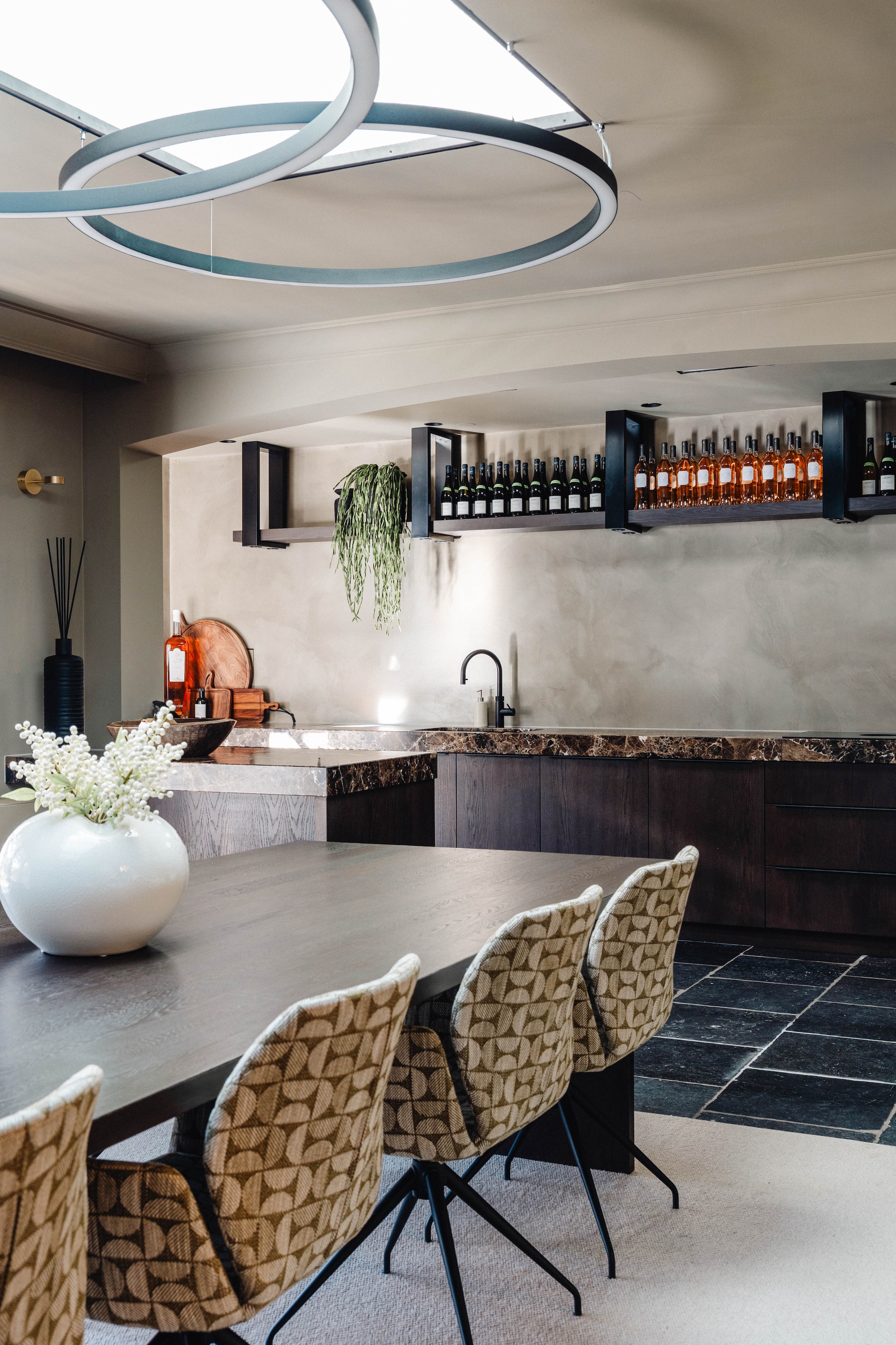 Eettafelstoelen Mobitec. Het wijnrek in de keuken van de werkruimte is op maat gemaakt van donker hout. Stijlvol Wonen 9-2025 | fotografie Stie de Neve