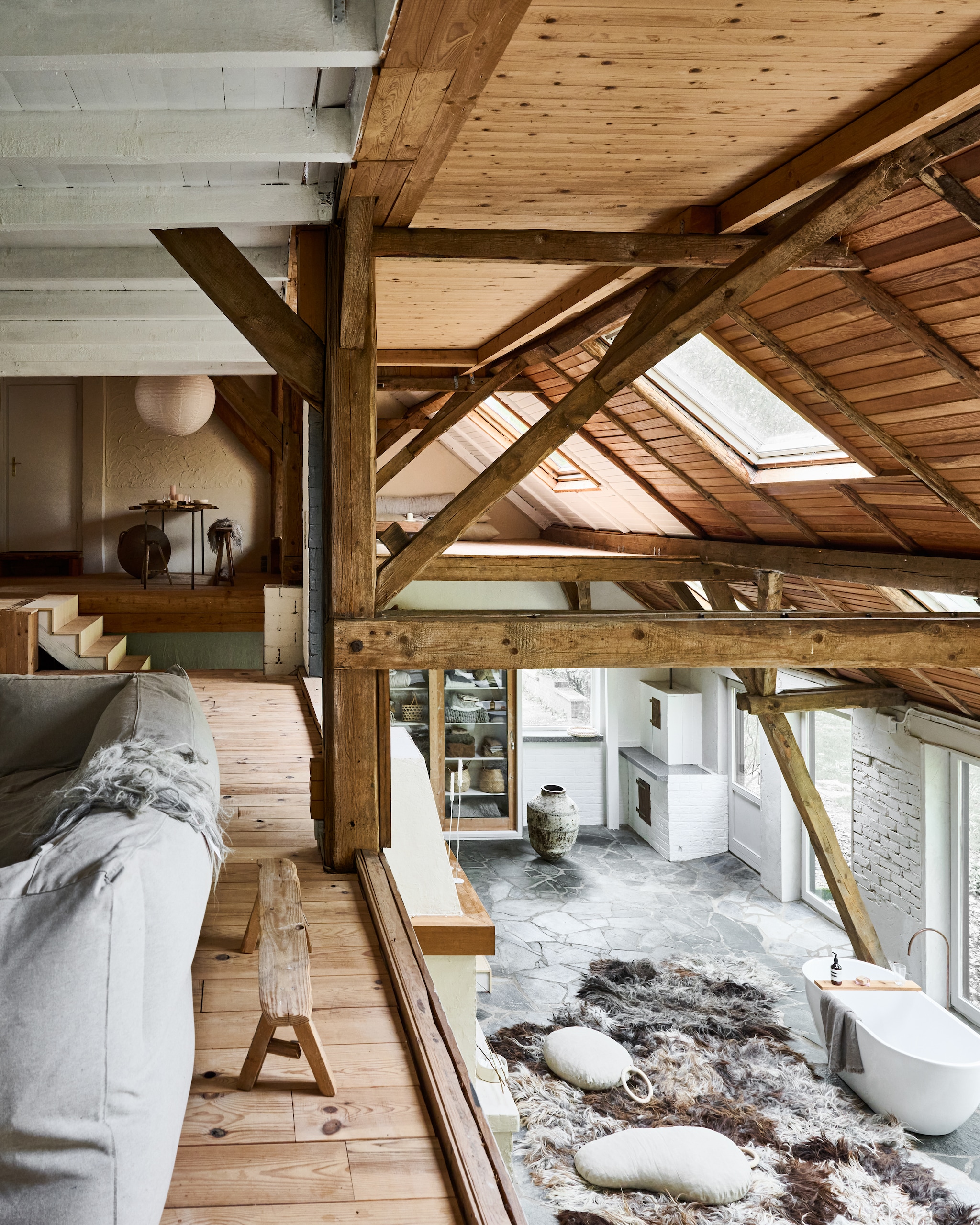 Vloer beneden flagstones Sikis Blue van Giraffa. Bank Bryck. Houten bankje, vloerkleed en vloerkussens Vacht van Vilt. Bad Marktplaats. Olijfolievaas antiek. Kast uit een school uit de jaren 30. Staande kandelaars K’willem in huis. vtwonen 12-2025 | styling Marianne Luning | fotografie Sjoerd Eickmans