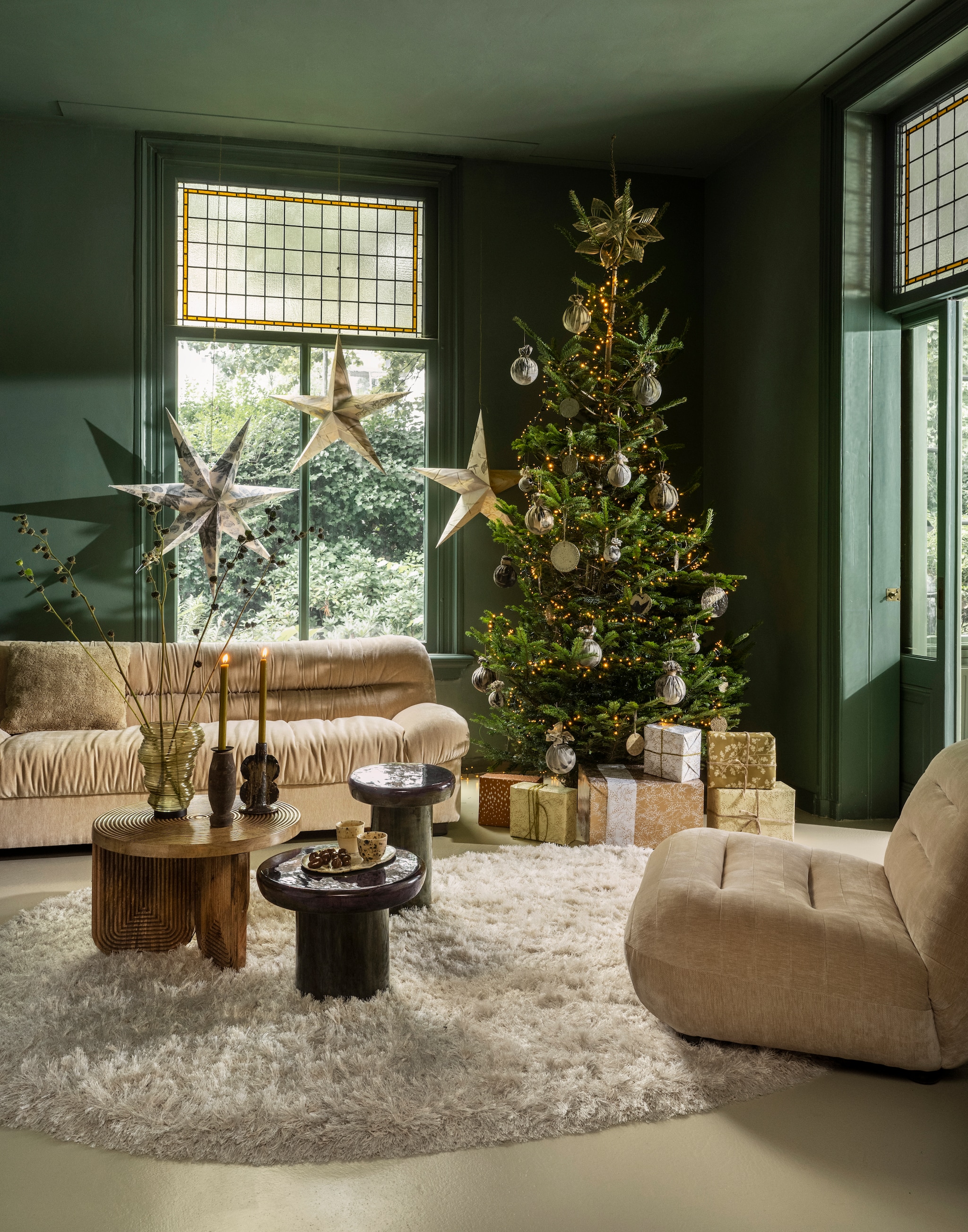 Dutchbone bank Douglas, velours, beige, 214x103x78 cm (lxbxh) € 2595,-, fauteuil Wyatt, velours, beige, 101x87x70,5 cm (lxbxh) € 869,-, bijzettafels Mush, mangohout, groen, 35x45 cm (Øxh) en 45x35 cm (Øxh) € 149,- en 189,-, Sfeer voor jou lichtsnoer, groen, 2 m € 90,-, J-Line vaas Tornado, glas, groen € 40,40, kandelaar Naga, keramiek, bruin € 30,40 (shop.vtwonen.nl). Zuiver vloerkleed Tasty, hoogpolig wolmix, wit, 200x290 cm (lxb) € 765,- (zuiver.com). Housecraft salontafel, mangohout, bruin, 60x40 cm (Øxh) € 299,- (housecraftliving.com). Ompak cadeaupapier (kookwinkel.nl). Ambermaakt kerstballen, textiel, ecoprint, klein€ 17,-, groot € 25,-, kerststerren, papier, ecoprint, naturel, vanaf € 250,- (ambermaakt.nl). @carolinelovesceramics kerstballen plat, keramiek, naturel, vanaf € 6,-, bord, ovaal, keramiek € 20,-, kopjes, keramiek € 14,-(@carolinelovesceramics). Madam Stoltz kandelaar, geüpcycled hout, set van 3 € 24,75 (madamstoltz.nl). Deens kerstster, bamboe € 17,25 (deens.nl). vtwonen 11-2025 | styling Marianne Luning | Stan Koolen