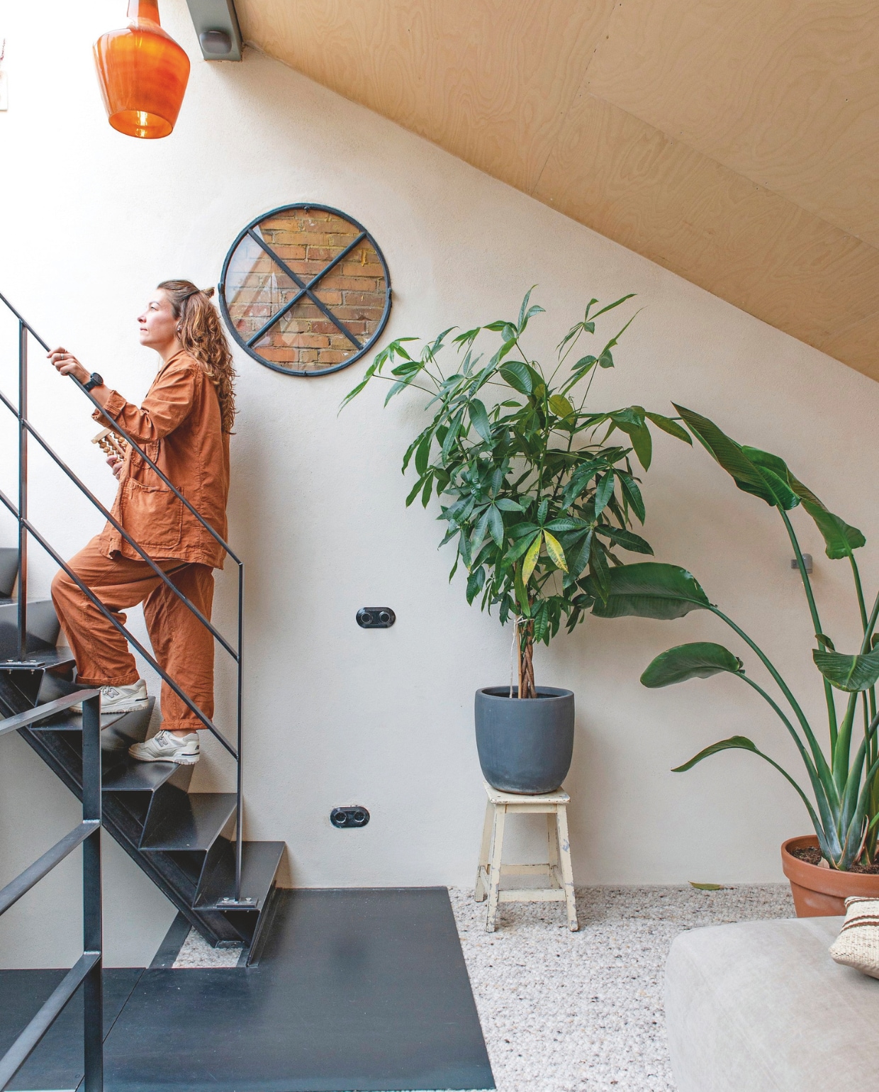 Grijze plantenpot Intratuin, vloerbedekking Steps and Tones via JB Woonstijl, kruk vintage, bank Fést, kussen The James, hanglamp HKliving. vtwonen 9-2025 | fotografie Caroline Coehorst
