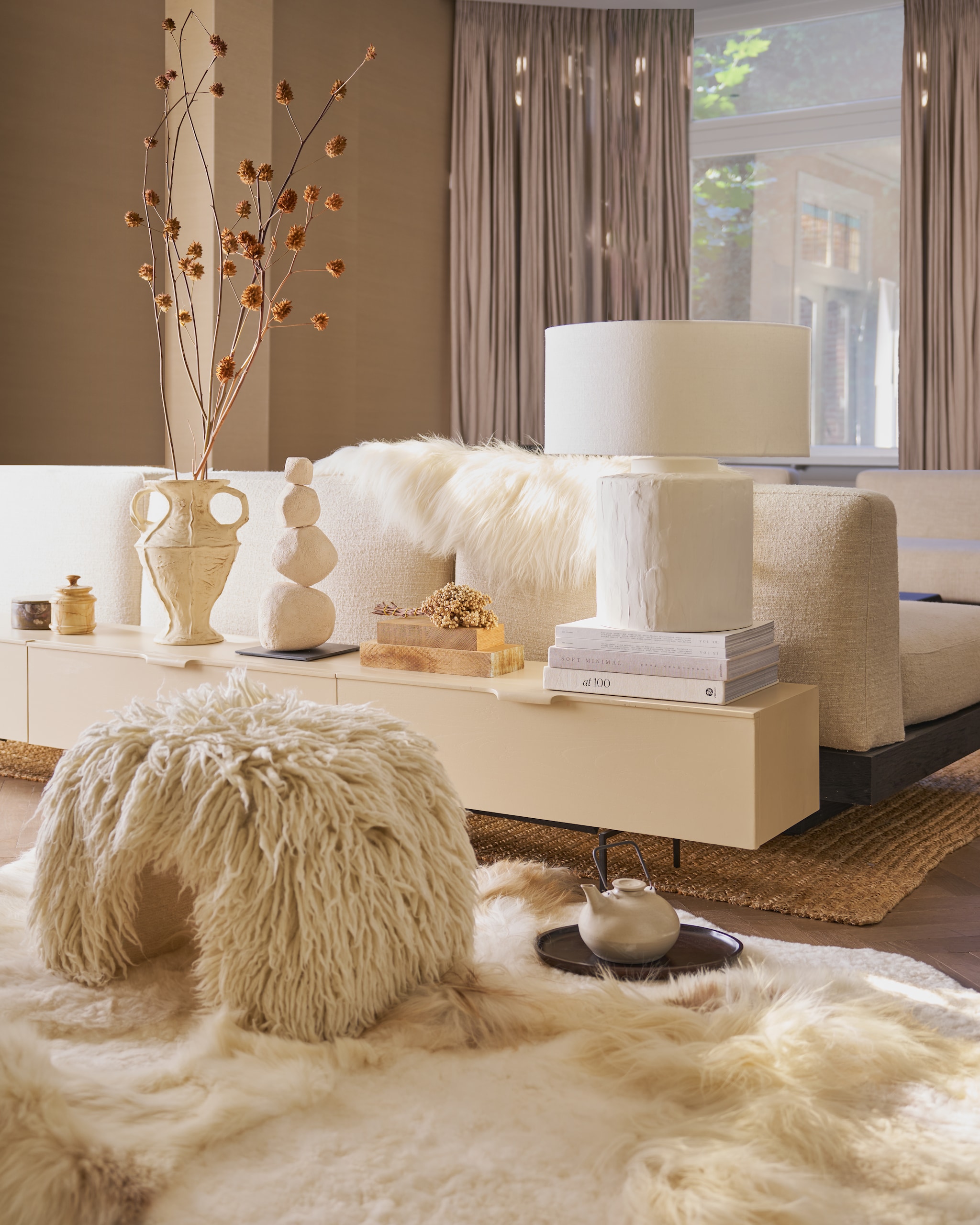 HKliving dressoir, hout, zand, 250x30x36 cm (bxdxh) € 1295,-, vaas New Classics, keramiek, cream € 79,95 (hkliving.com). Vachtenspecialist schapenvacht vloerkleed, melange wit, 180x120 cm (lxb) € 695,-, schapenvacht IJslands op bank, wit € 79,95 (vachtenspecialist.nl). Urban Nature Culture poef Bjarne, wol en katoen, offwhite € 249,99, tafellamp Masson, katoen en keramiek, wit € 189,- (shop.vtwonen.nl). Mette Sophie object Crains, keramiek, crème, prijs op aanvraag (mettesophie.com). Serax bank Rudolph, ontwerp van van Vincent Van Duysen, hout en bouclé, bone, 93x112x72 cm (lxbxh), per element € 3099,- (serax.com). Zara Home dienblad, donker hout € 17,99 (zarahome.com). Marktplaats potjes, steen (marktplaats.nl). Overig privébezit. vtwonen 12-2025 | styling Cleo Scheulderman | fotografie Jeroen van der Spek