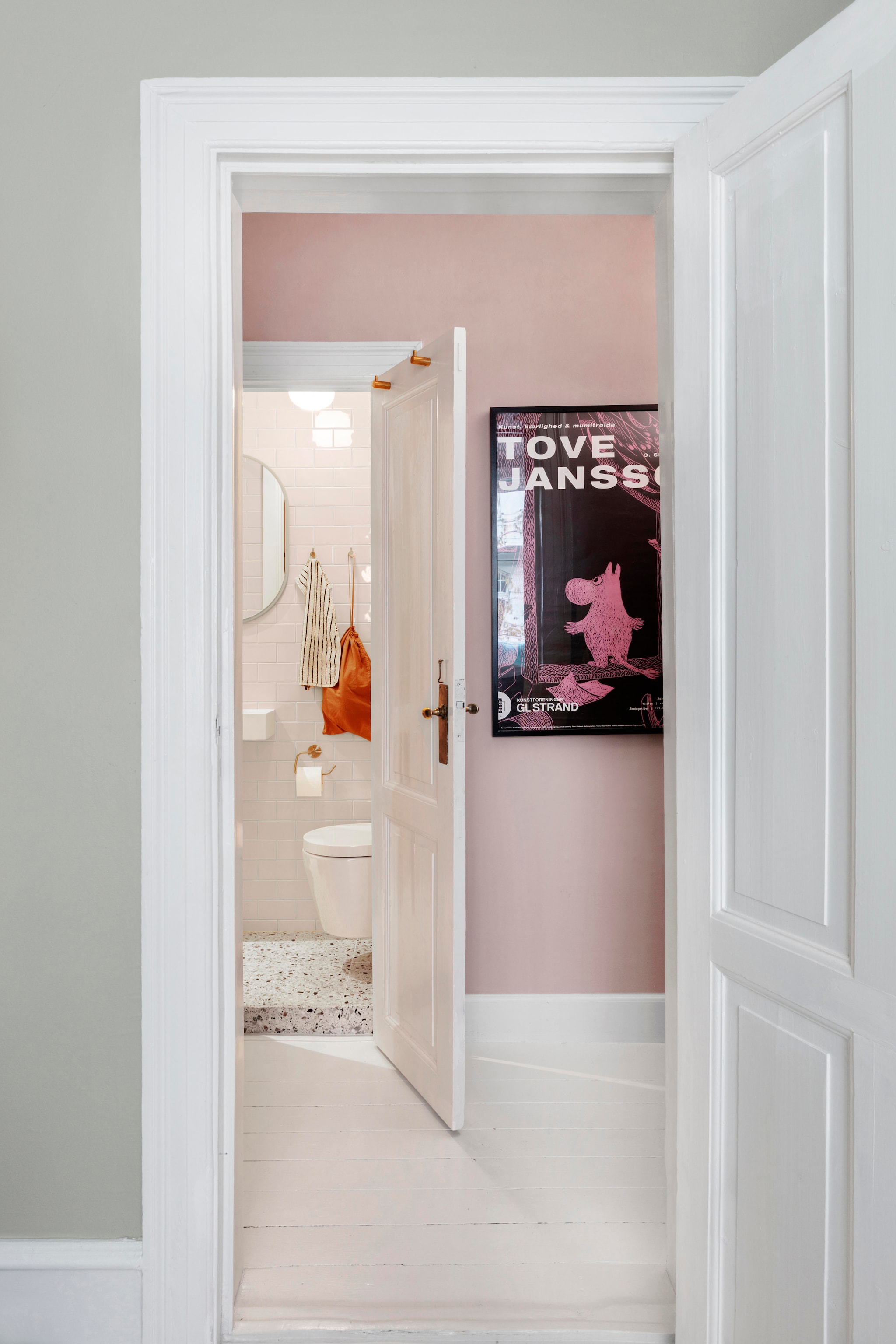 Illustratie van Tove Jansson. Wasbak, toiletrolhouder Grohe. Spiegel Montana furniture. Handdoek Tekla Fabrics. vtwonen 01-2026 | productie Living Inside | styling Rikke Graff Juel | fotografie Christina Kayser O.