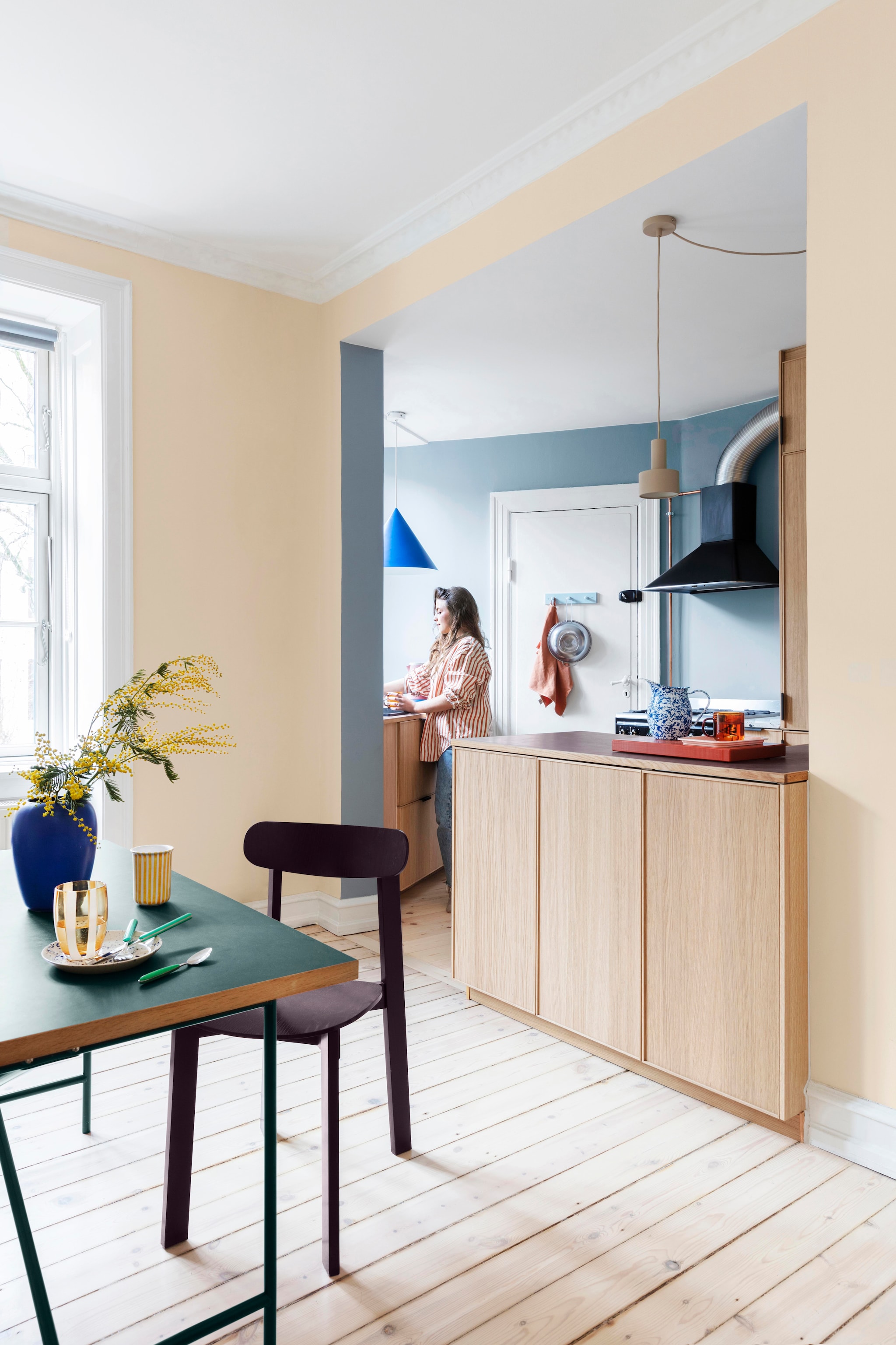 Keuken Ikea. Linoleum werkblad Forbo. Stoel Wait to be seated. Blauwe lamp Stilleben architects. Beige lamp  Collect Lighting van Ferm Living. Kan gekocht bij shop Dora. Rode beker en dienblad Hay. Roze schaaltje Søstrene Grene. vtwonen 01-2026 | productie Living Inside | styling Rikke Graff Juel | fotografie Christina Kayser O.