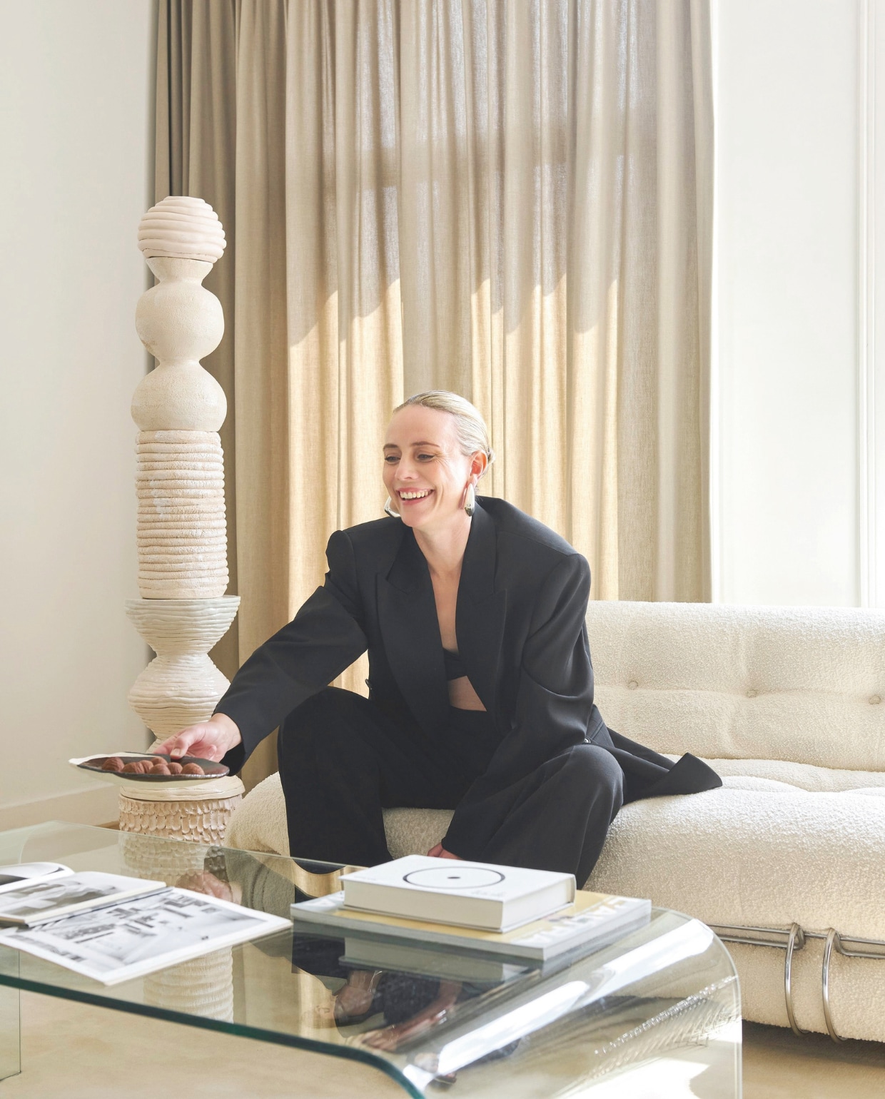 Gloria draagt een pak van Phoebe Philo. Bank Soriana van Cassina. Stijlvol wonen 9-2025 | styling Marianne Luning | fotografie Kasia Gatkowska | tekst Anneleen Peeters
