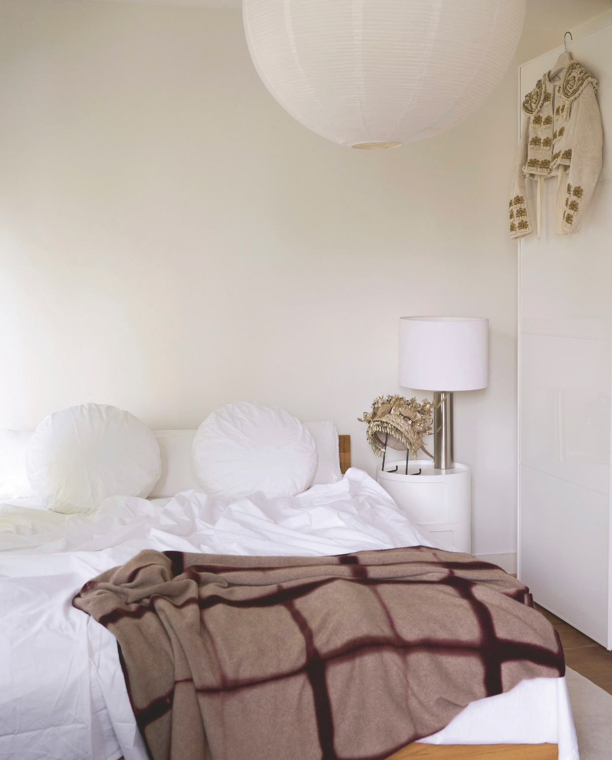 Kussens Suite702. Plaid via Mobilia. Kroon van de Miao tribe souvenir uit China. Lamp online vondst. Nachtkastje Kartell. Aan de kast hangt een uniek vest van Gloria, volledig geborduurd met gerecupereerde kralen. Plafondlamp Hay. Bed Objekte unserer tage. Stijlvol wonen 9-2025 | styling Marianne Luning | fotografie Kasia Gatkowska | tekst Anneleen Peeters