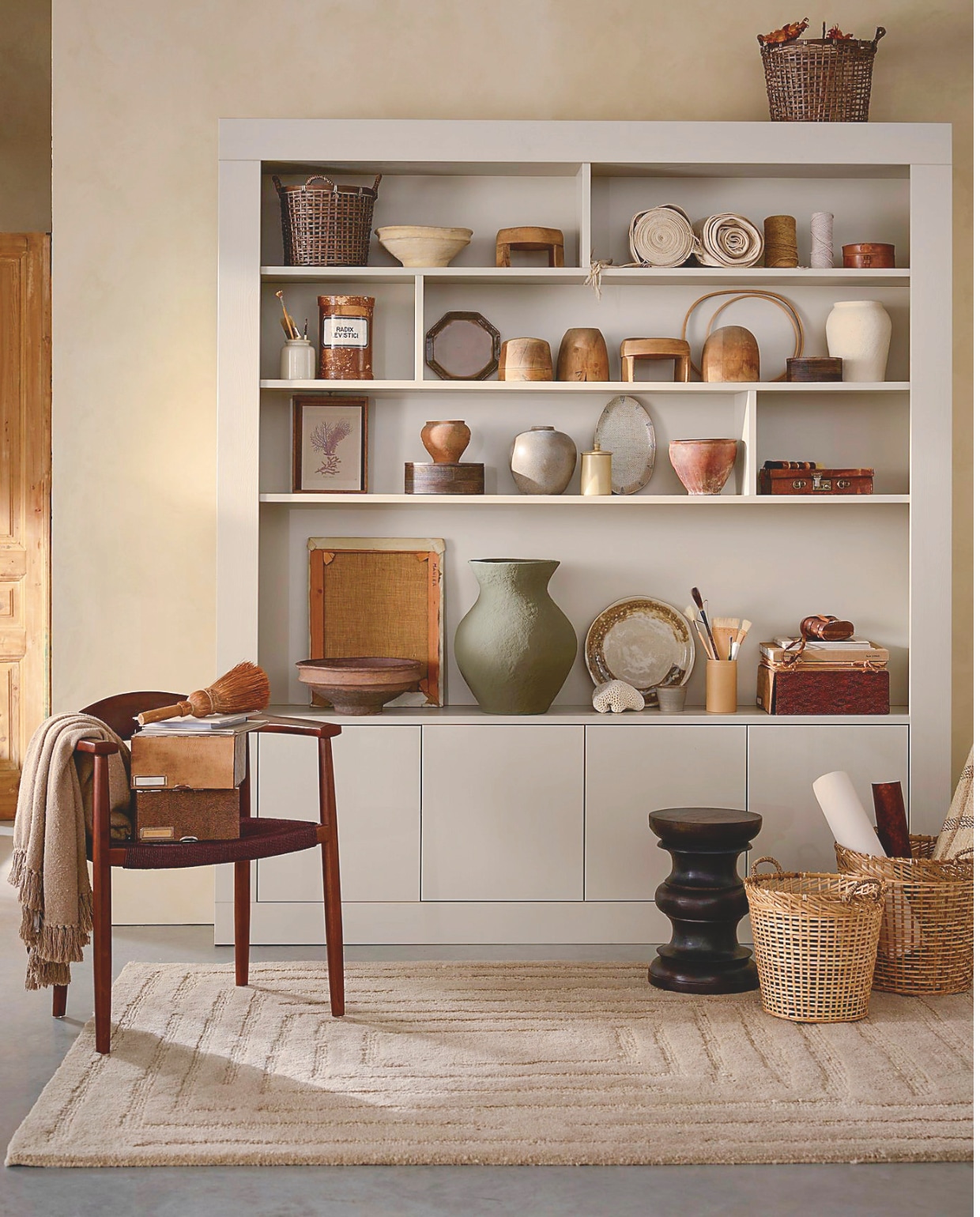 vtwonen wandkast Wallcover, grenen, dust, 210x31x229 cm (bxdxh) € 1499,-. eetkamerstoel Embrace, hout, donkerbruin, 64x53x76 cm (bxdxh), set van 2 € 558,-. 
M.m.v. burbriantiek.nl (stofrollen, hoedenmallen, archiefdozen, kruiken), urbannatureculture.com (grote papier-maché vaas), woood.nl (vloerkleed, bijzettafel),madamstoltz.dk (manden, plaid), zarahome.com (ronde dozen, papier-maché schaal, schalen). Overig privébezit. vtwonen Landelijk 10-2025 | styling Cleo Scheulderman | fotografie Jeroen van der Spek