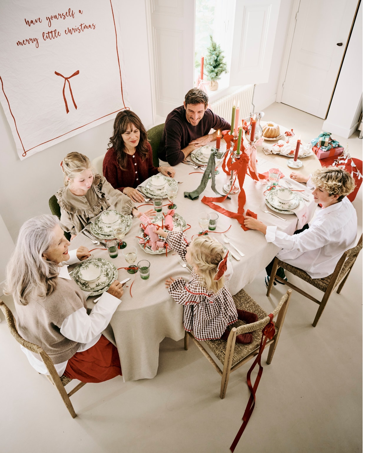 Zara Home servies, porselein, groen, per stuk vanaf € 6,99, waterglazen € 3,99, wijnglazen € 3,99, tafelkleed, linnen € 69,99 (zarahome.com). Kleding Helena (moeder): Bellerose vest (orangebag.nl), Zara rok (zara.com). Kleding Sebastien (vader): Massimo Dutti trui, wol, jeans, schoenen (massimodutti.com). Kleding Willemijn (oma): Massimo Dutti rok, blouse, spencer (massimodutti.com). Kleding Charlie (zoon): Zara blouse, broek (zara.com). Kleding Phie (oudste dochter): Marmar Copenhagen jurk (marmarcopenhagen.com). Kleding Saar (jongste dochter): Sissel Edelbo jurk (sissel-edelbo.com). vtwonen kerstboek 2025 | styling Danielle Verheul | fotografie Sjoerd Eickmans