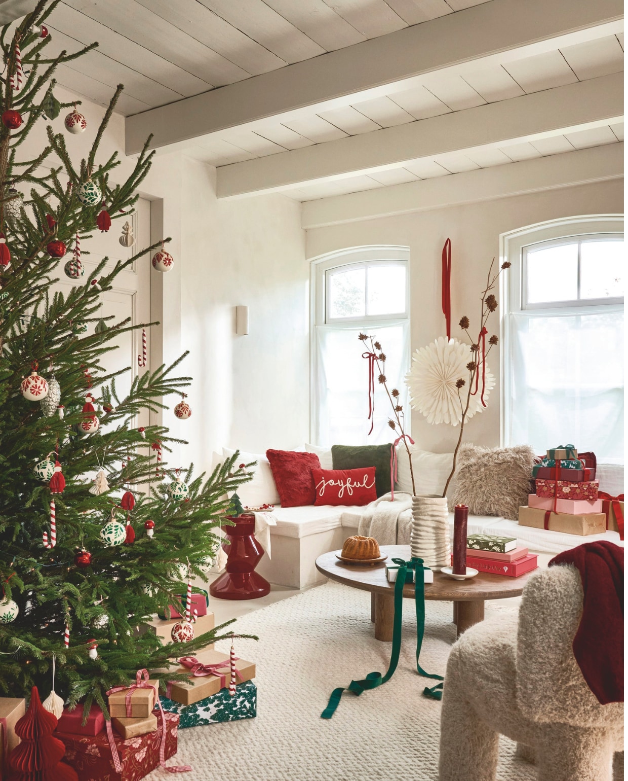 Bungalow ornament kerstboom, papier, rood € 20,-, opbergdozen, rood en roze met illustraties, set van 2 € 53,75, ornament kerstboom, papier, groen € 12,75, ster XL, papier € 67,- (bungalow.dk). Leuk Verpakt pakpapier dennenbomen € 3,25 (leukverpakt.nl). Loods5 vloerkleed, wit € 825,-, salontafel Manu, hout, 105x95x32 cm (lxbxh) € 950,- (loods5.nl). Polspotten bijzettafel Zig Zag, kunststof, rood € 400,- (polspotten.com). Zara Home schaal, keramiek € 15,99, vaas, geribbeld aardwerk, wit € 59,99 (zarahome.com). Kulu Club servetten, linnen met rode strik, set van 2 € 23,95, J-line kussens rood met vacht € 38,95, rood Joyful € 39,- en groen met vacht € 36,95, Urban Nature Culture bord op pootjes, hout € 34,99, kandelaar, hout € 21,99, Bodini fotoboek, rood € 55,-, vier-op-een-rij spel in roze doos € 45,- (shop.vtwonen.nl). H&m kussen, vacht, crème € 24,99, fauteuil Relax compact, kunststof, crème, 57x57x66 cm (bxdxh) € 369,- (hm.com). Søstrene Grene geschenkdozen, papier, roze en donkerroze, per stuk vanaf € 4,18 (sostrenegrene.com). American Vintage vest, mohair, bordeauxrood € 129,99 (americanvintage.com). vtwonen kerstspecial 2025 | styling Danielle Verheul | fotografie Sjoerd Eickmans