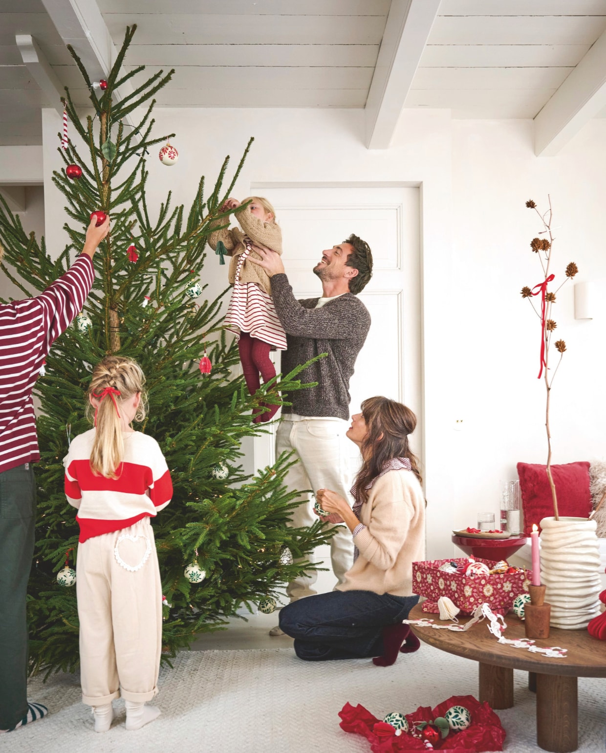 Urban Nature Culture kandelaar, hout € 22,99, J-line kussen, vacht, rood € 38,95 (shop.vtwonen.nl). Bungalow opbergdozen, rood en roze, set van 2 € 53,75, kerstornamenten, papier, wit, set van 3 € 16,25, guirlande ganzen, papier € 11,25 (bungalow.dk). Loods5 vloerkleed, wit € 825,-, salontafel Manu, hout, 105x95x32 cm (lxbxh) € 950,- (loods5.nl). Polspotten bijzettafel Zig Zag, kunststof, rood € 400,- (polspotten.com). Kleding Helena (moeder): Bellerose vest (orangebag.nl). Zara geruite top (zara.com). Massimo Dutti jeans (massimodutti.com). Kleding Sebastien (vader): Massimo Dutti vest, t-shirt, broek (massimodutti.com). Kleding Charlie (zoon): Zara top, jeans (zara.com). Kleding Phie (oudste dochter): Zara gestreepte trui, broek met hart (zara.com). Kleding Saar (jongste dochter): Zara vest (zara.com), Lil’atelier jurk (lilatelier.com). Overig privébezit. vtwonen kerstspecial 2025 | styling Danielle Verheul | fotografie Sjoerd Eickmans