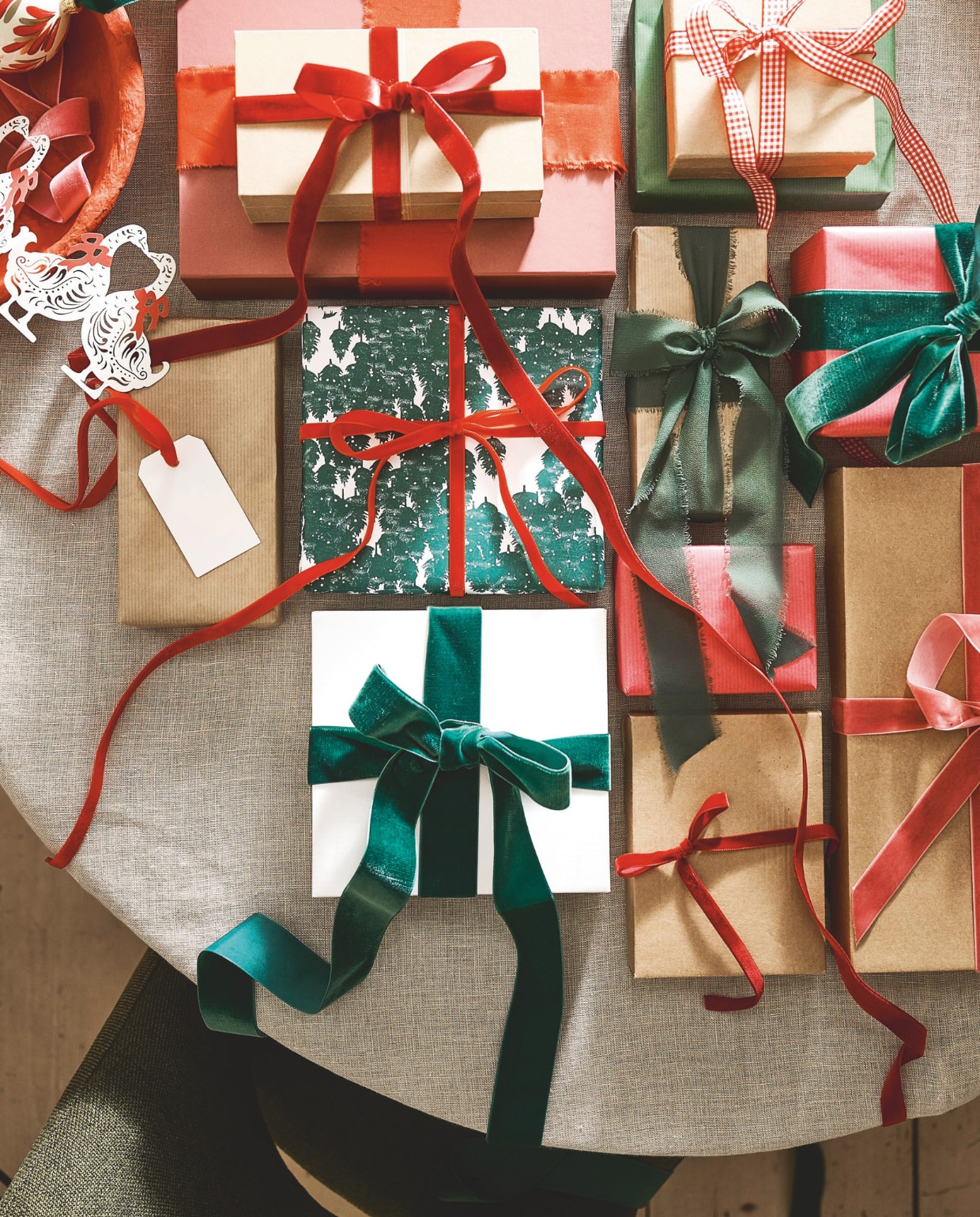 Polspotten eetkamerstoel Cosy, forest green, 57x63x83 cm (bxdxh) € 400,- (polspotten.nl). J-line schaal, papier-maché, rood, set van 3 € 138,- (shop.vtwonen.nl). Bungalow guirlande ganzen, papier € 11,25 (bungalow.dk). Leuk Verpakt inpakpapier dennenbomen, per rol € 3,25 (leukverpakt.nl). vtwonen kerstspecial 2025 | styling Danielle Verheul | fotografie Sjoerd Eickmans