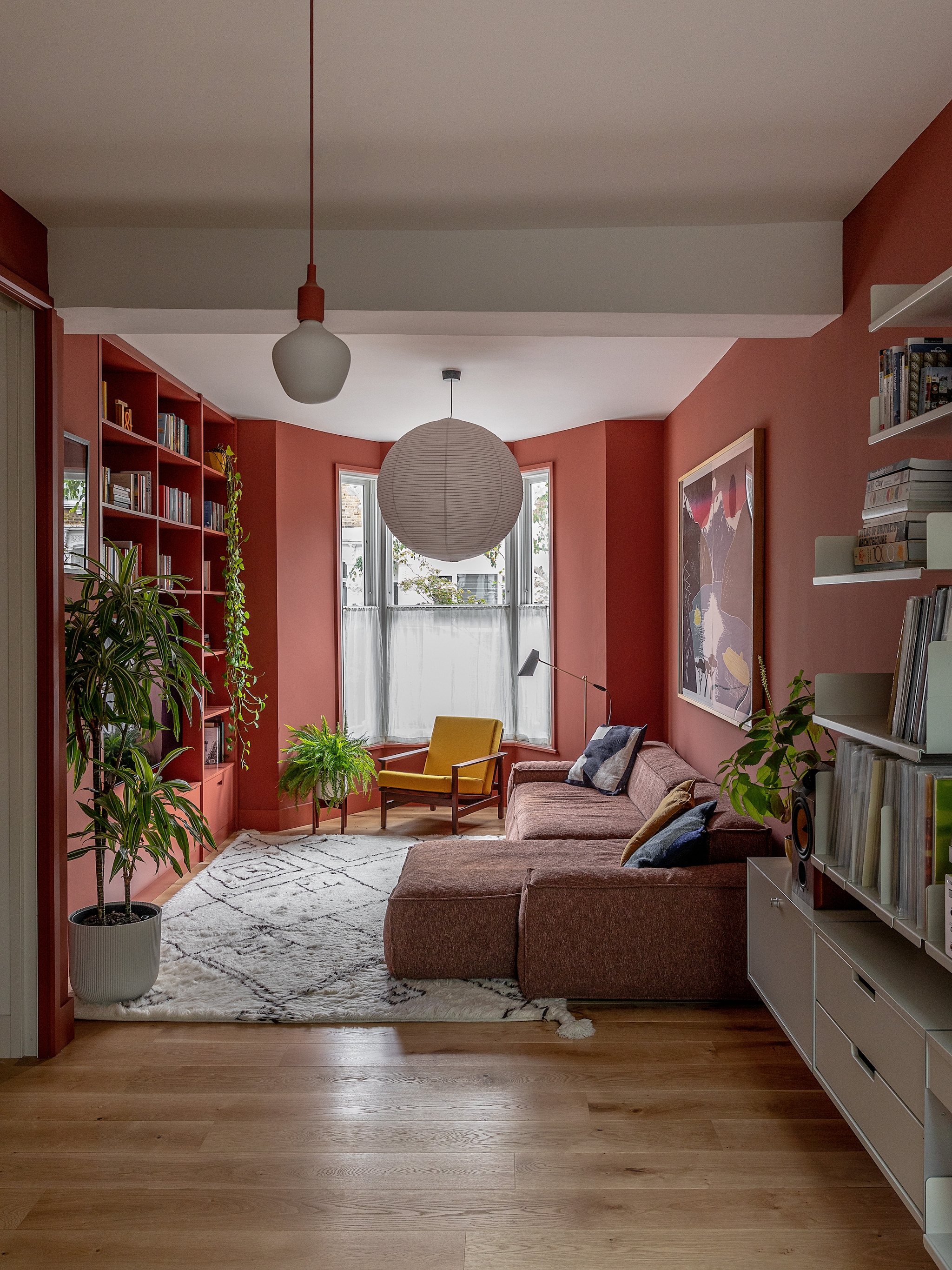 Plantenpotten Elho. Lampenkap bol van rijstpapier Hay. Staande lamp Birdie van Northern. Kussens Ferm Living. Gele stoel vintage. Bank Planar van The Conran Shop. Vloerkleed Layla van Soho Home. Gordijnen East London Cloth. Houtsnede Sadie Tierney. vtwonen 02-2026 | fotografie Taran Wilkhu | productie Living Inside