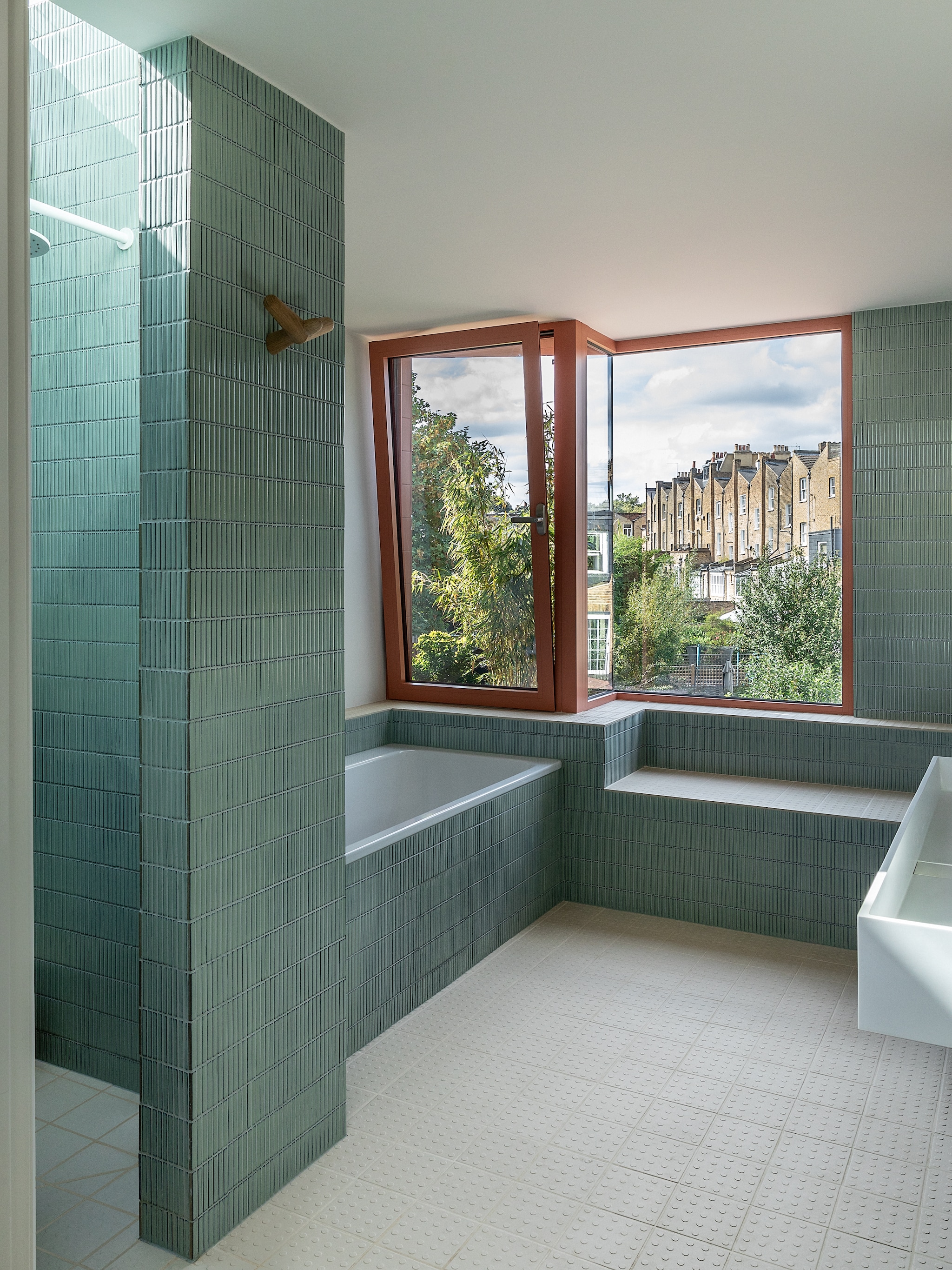 Wastafel en kranen Lusso Stone. Spiegel James Dowie. Wandtegels Iggy in Sage van Mandarin Stone. Vloer Dorset Woolliscroft. Vloer en trap Havwoods. Muurlamp Astro Lighting. vtwonen 02-2026 | fotografie Taran Wilkhu | productie Living Inside