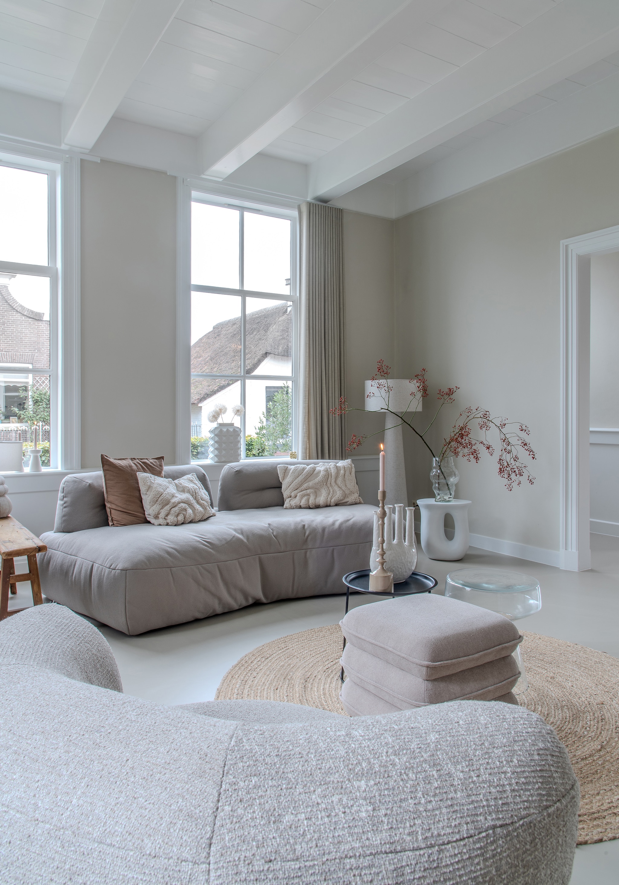 Bank en fauteuil Bank Boutique. Poef Leen Bakker. Glazen bijzettafel Sissy-Boy. Vloerkleed Karwei. Lamp Kwantum. Glazen vaas HKliving. Vaas voor raam Jonathan Adler. Droogbloemen Tof Bloemen. Vaas en kandelaar Light & Living. Gordijnen Meer Wonen. Gietvloer Vloertechniek Hoogeveen. vtwonen 02-2026 | styling Peet Styling | fotografie Joyce Vloet