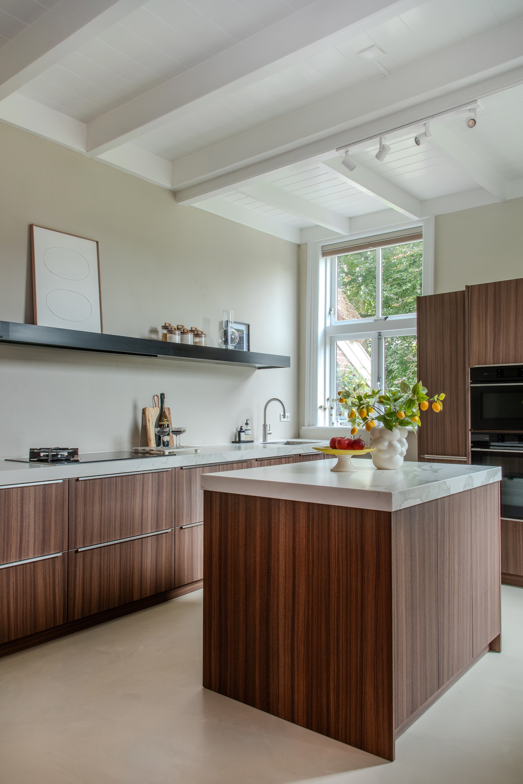 Keuken gewrapt door Veenstra Reclame. Werkblad composiet. Afzuigplank Shelf van Falmec. Lepel en vork H&m Home. Potjes Action. Schaal Des Pots. Snijplank Things I Like Things I Love. Gietvloer Vloertechniek Hoogeveen. vtwonen 02-2026 | styling Peet Styling | fotografie Joyce Vloet