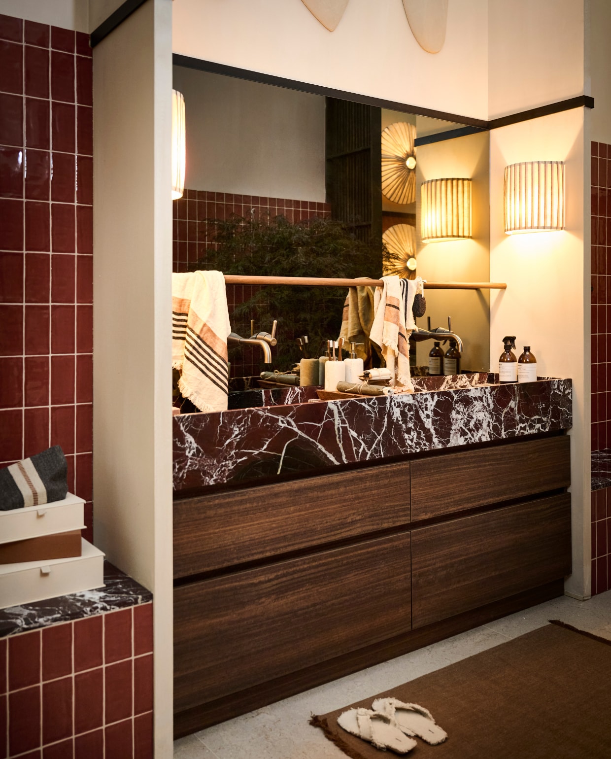 Verf op latten Graphite CC002, muurverf Calce CC011 en Palazzo CC049 Calcare Italia (Carte Colori). Wandtegels Pradolongo Garnet Brillo (Heritage via Ton Scholten). Muurtegels Icon Sand heel en Icon Sand hoek, vloertegels Limestone Cream, beige bad, badkraan Cone, douchekop Cone, douchethermostaat Cone, doucheomsteller Cone, badbrug Wood (Decor Walther), onderkast Koper Eiken op maat (Sanibell), wastafel Rosso Levanto op maat (Grillo), marmeren plateau M, marmeren blad Rosso Levanto (Grillo) en spiegel op maat (AGC) allemaal via Ton Scholten. Muurlamp The Baco Abaca en Baco Abaca fibre (Couvaloup). Zeepjes, wierook en jurk (Sukha). Wandrekken op maat en houten steunen (Combitex). Grote bijzettafel Minimez L en kleine bijzettafel Minimez M (Janice Jill). Meditatiebundel, zeep Le Botaniste by Orris, riem, schoonmaakproducten Attirecare, wierook Palo Santo en wierookhouder by Annemiek Boot (Atelier Sukha). Slippers linnen, stenen beker, zeeppomp, knoppen, vloerkleed wol en katoen, spons, opbergbox, wierook en zwarte steen (Zara Home). Muurdecoratie Totems 3D en Totems (Atelier de Rijk). Plantenpot Moya M by Domani (Piet Boon). Boom roze Acer en planten (Nieuwkoop Europe). Stenen in bloempotten Yellow Sun Marble (Splitkorrel). Muurdecoratie Zwam 2-delig, roze mini zwamvorm en koraalvorm op steen (Elsa Visser). Gestreepte plaid Luc, wit gestreepte handdoek The Belgian Towel Inyo, wit gestreepte gastendoek The Belgian Towel Inyo, grijs gestreepte gastendoek The Belgian Towel Black Stripe, etui Luc en loper (Libeco). Strijkijzersnoer zwart linnen, light fitting zwart kunststof E27, ledlamp goud A60 en ledlamp goud G80 (Kynda Light). Wierookhouder met twee gaten (LaNena). Bruine stenen bol (Flinke Vintage). Bruin klein vaasje en bruine bakjes (Sandra van Riet). Kunstwerken Ripple (Boketo.art).