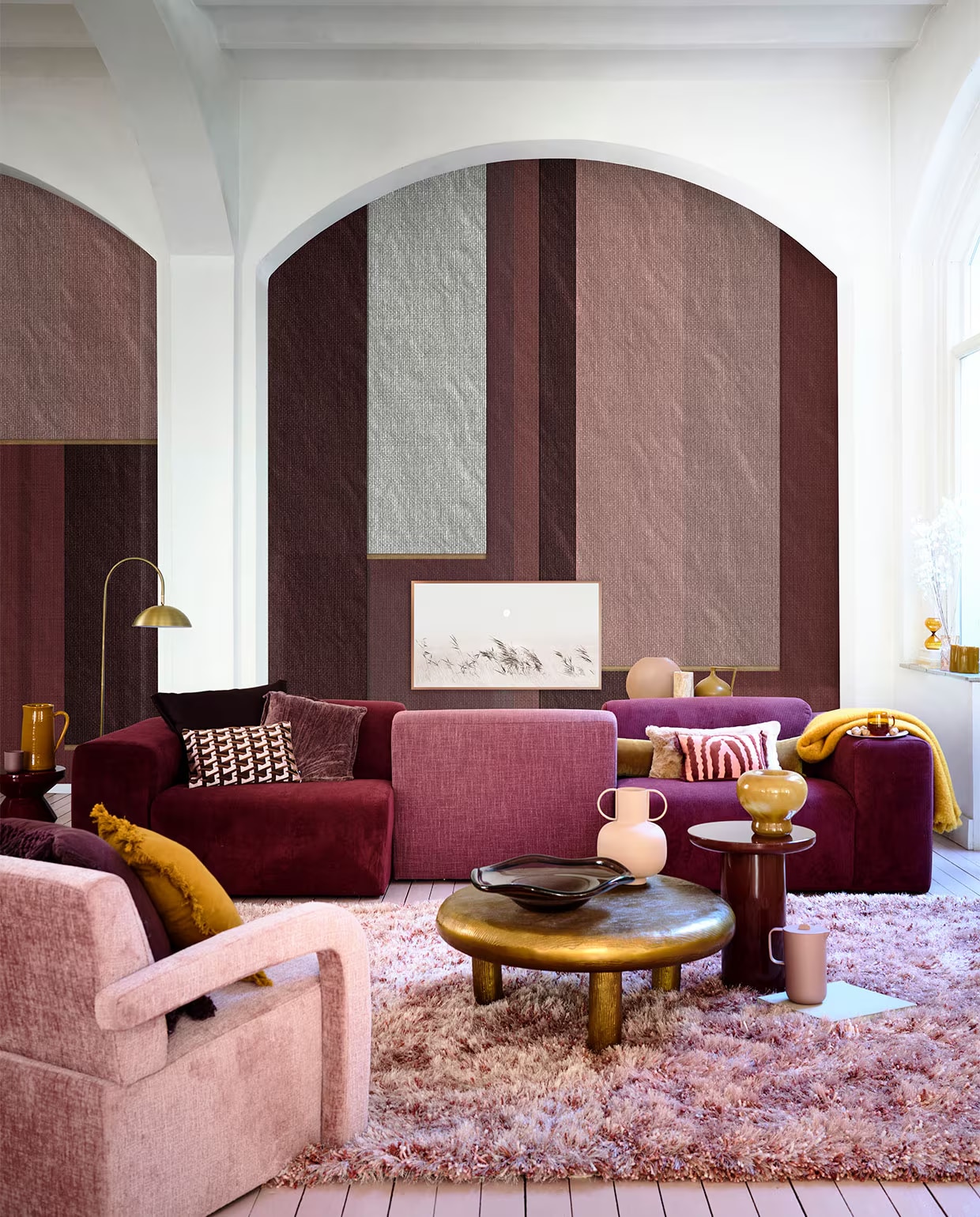 Behang Veli, per m2 € 115,- (wallanddeco.com). Wijnrode en roze bank Oscar, modules vanaf € 375,- (loods5.nl). Fauteuil € 549,-, roze mok € 26,99, roze kan € 29,99, roze bord € 33,49 (jotex.com). Goudkleurige salontafel Thick Disk € 1295,-, glazen schaal € 235,-, bordeauxrode bijzettafel Mob € 475,-, bordeauxrode bijzettafel € 325,- (polspotten.com). Polyester vloerkleed Berino van Linie Design, 230x160 cm € 304,50 messing vloerlamp Jupiter van vtwonen € 166,50 (vtwonen.nl). Auberginekleurig kussen met rafelrand € 54,99, roze vaas met grepen € 29,99, glazen theeglas € 7,99 (sissy-boy.com). Geel kussen met rafelrand € 29,99 (zarahome.com). Gele keramieken kan € 48,50, gele mohair deken € 225,- (paviljoennoord.com). Auberginekleurig kussen € 109,-, kussen met art-decoprint € 49,95, kussen met roze en rode print € 34,95  (loods5.nl/design). Paars fluwelen kussen € 49,90 (brechtjeolsthoorn.nl). Roze vacht kussen € 85,- (homestede.nl). Ronde roze vaas € 59,-, olijfkleurige organische blokkaars € 29,- (festamsterdam.com). Travertin vaas € 89,-, glazen zandloper € 27,90 (letoile.store). Okergele kruikvaas € 47,95  (hkliving.nl). Okergele glazen vaas € 24,99 (hm.com). Overig privébezit. vtwonen 11-2022 | styling Danielle Verheul | fotografie Sjoerd Eickmans