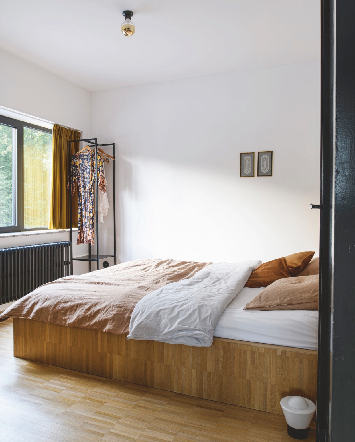 Eikenhouten XL-bed zelf ontworpen en op maat laten maken door een timmerman. Beddengoed H&m Home. Gouden fluwelen gordijnen Hema. Borduurwerkjes gemaakt door een tante. Tafellamp, sierkussens en porseleinen stopcontact Zangra. Soortgelijk kledingrek Nordal. vtwonen 12-2025 | styling Marit Saladini | fotografie Louis Lemaire