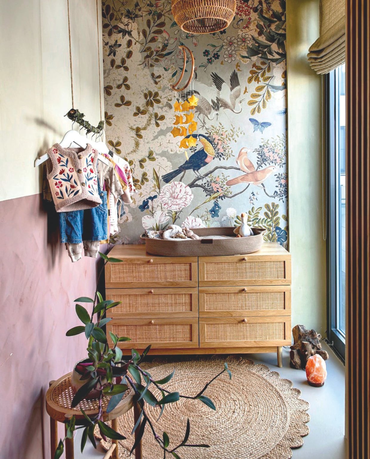 Op de muur minerale kalkverf kleur olijfgroen en roze De Ru. Ladenkast Beliani. Hanglamp Uma Cantik. Behang Poespas. Juten kleed La Redoute. Kruk kringloop. Raambekleding Elle La. Verschoonkussen Yunioo. Mobile cadeaut van een vriendin. vtwonen 12-2025 | styling Annemieke Paarlberg | fotografie Caroline Coehorst | tekst Ina Babbé