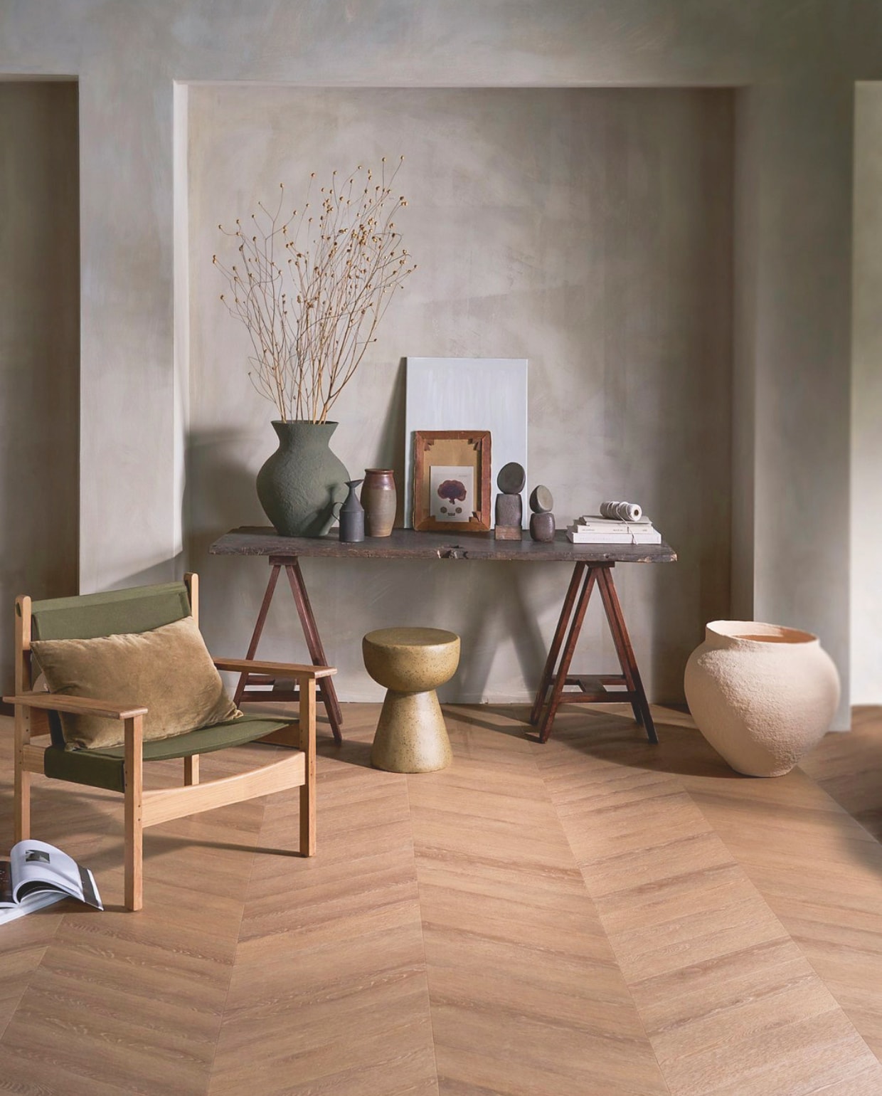 vtwonen pvc-vloer Noble, sunkissed, 53,8x11,7 cm, dryback per m² € 48,95.M.m.v. pietjonker.nl (schragen, tafel, kruk, zwarte kan, bruine pot), urbannatureculture.com (groene vaas, beige pot), hkliving.com (kruk, kussen, fauteuil Explorer). Overig privébezit. vtwonen 1-2026 | styling Cleo Scheulderman | fotografie Jeroen van der Spek