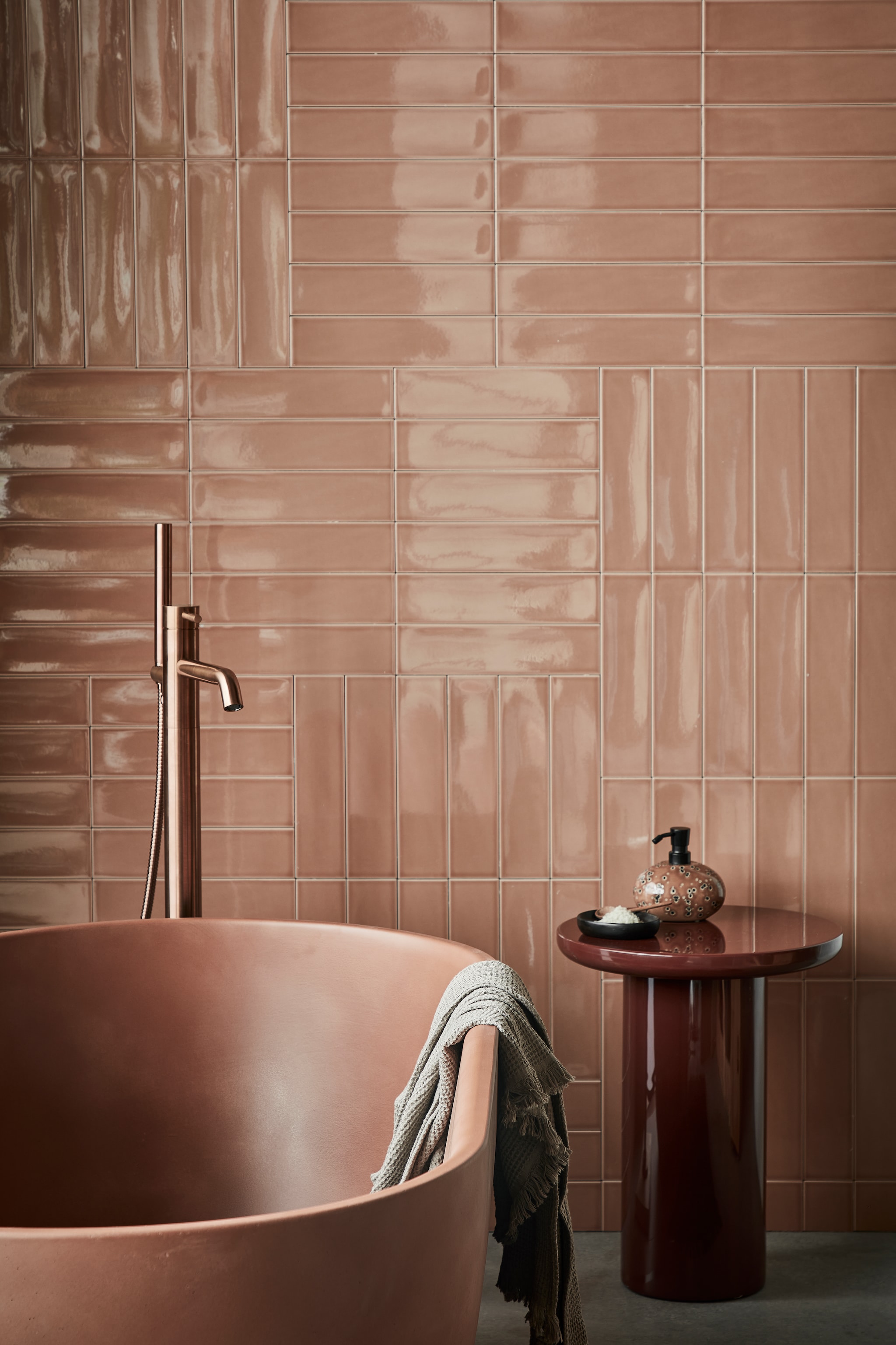 vtwonen collectie vloeren en tegels, Vloertegels Raw Grey, 80x80 cm per m² € 79,95, wandtegels achter bad Shapes Toffee glans, 7,5x30 cm per m² € 58,99, detremmerie.be (bad), polspotten.com (bijzettafel Mob), vtwonen.nl (badmat van Ferm Living, marmeren schaal en zeepdispenser Ugo van Aquanova), Uit de vtwonen badkamercollectie: vrijstaande badkraan Roma van Plieger. Overig privébezit. vtwonen 02-2023 | styling Sanne Ketelaar | fotografie Peggy Janssen