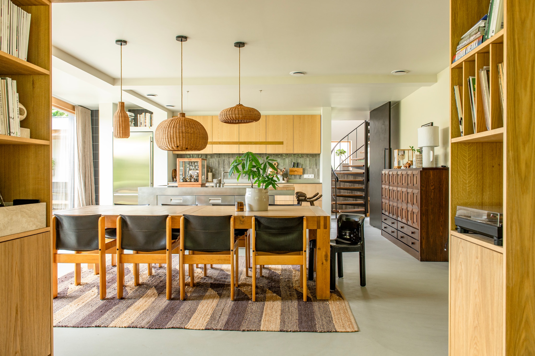 Eettafel Vnu van Linteloo. Vintage eetkamerstoelen Ibisco. Kunststof stoel Carlo Bartoli. Hanglampen Ferm Living. Keuken Arclinea. Plantenpot en geurkaars P.f. Candle via Bynord. Taatsdeur maatwerk. Gordijnen Le Rideau. Muurverf Bone en trapverf Ristretto van Pure & Original. vtwonen 04-2026 | styling Jeske Weel | fotografie Caroline Coehorst