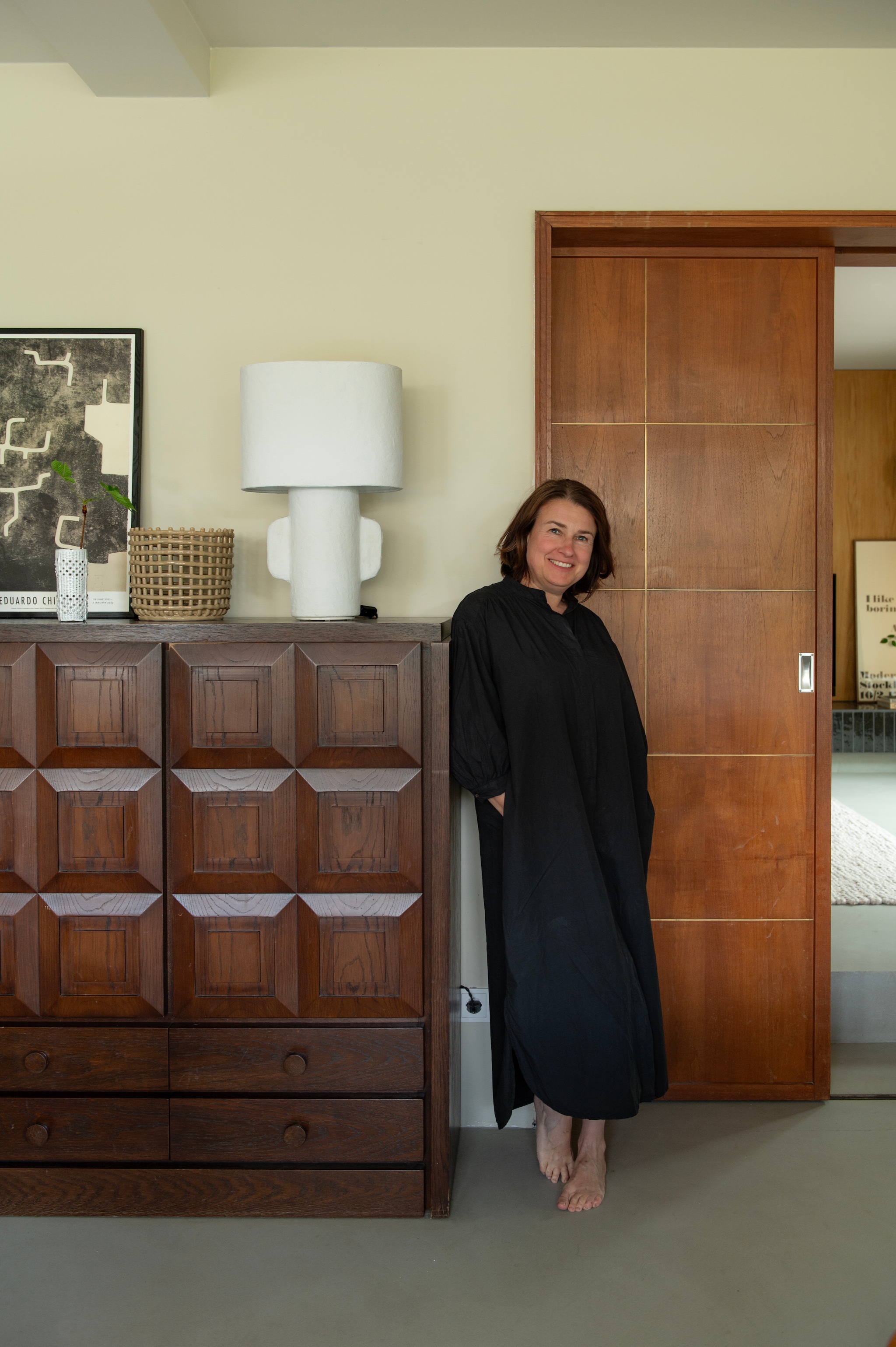 Soortgelijke vintage kast De Coene via Lab Design Vintage. Lamp Serax via Bynord. Mand Ferm Living. Tentoonstellingsposter Eduardo Chillida via Hauser & Wirth. Vaas Great Ceramics. Schuifdeur origineel. Wandkleur Neutral Ground van Pure & Original. vtwonen 04-2026 | styling Jeske Weel | fotografie Caroline Coehorst