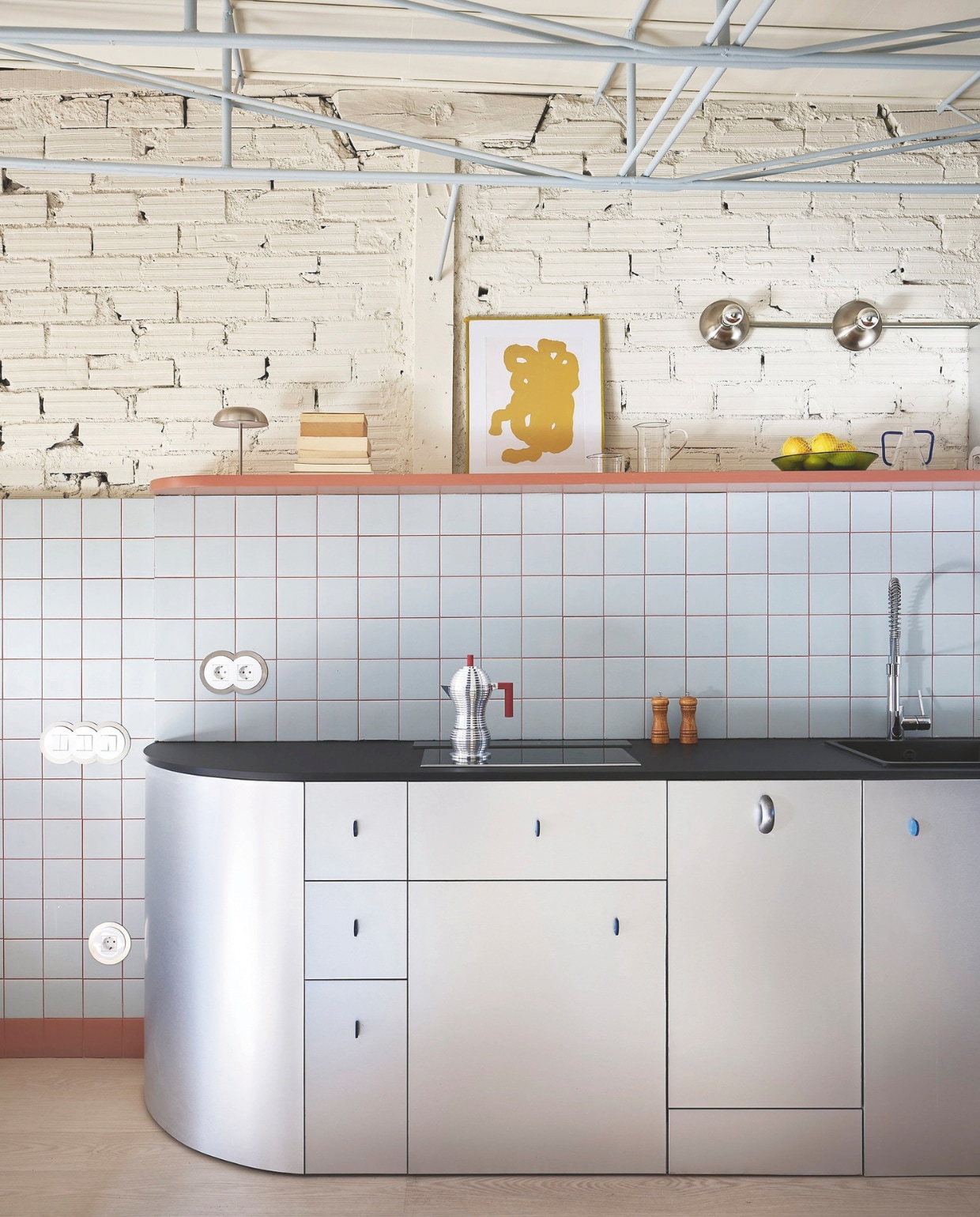 Maatwerk keuken met kastfronten van Formica bekleed met metaalfolie. De handgrepen, opgevat als kleine sculpturen, zijn met de hand vervaardigd door een lokale maker. Espressomaker Alessi. Print van een lokale kunstenaar. vtwonen 01-2026 | fotografie Germán Sáiz