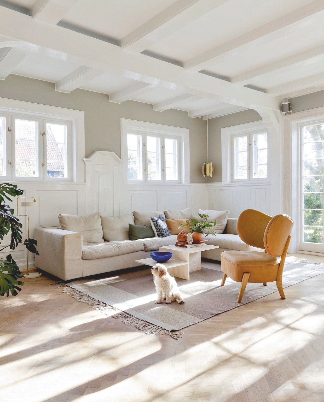 Bank Eilersen tweedehands. Fauteuil Tmbo van Mazo. Salontafel Ferm Living. Hanglamp Divan 2 van Lyfa. Vloerlamp Petite Machine van Made by Hand. Vergelijkbaar vloerkleed Carpet Dream van Zuiver. Decoratie vintage. Muurkleur Washed Linen van Jotun. vtwonen 02-2026 | styling Rikke Graff Juel | fotografie Christina Kayser O.