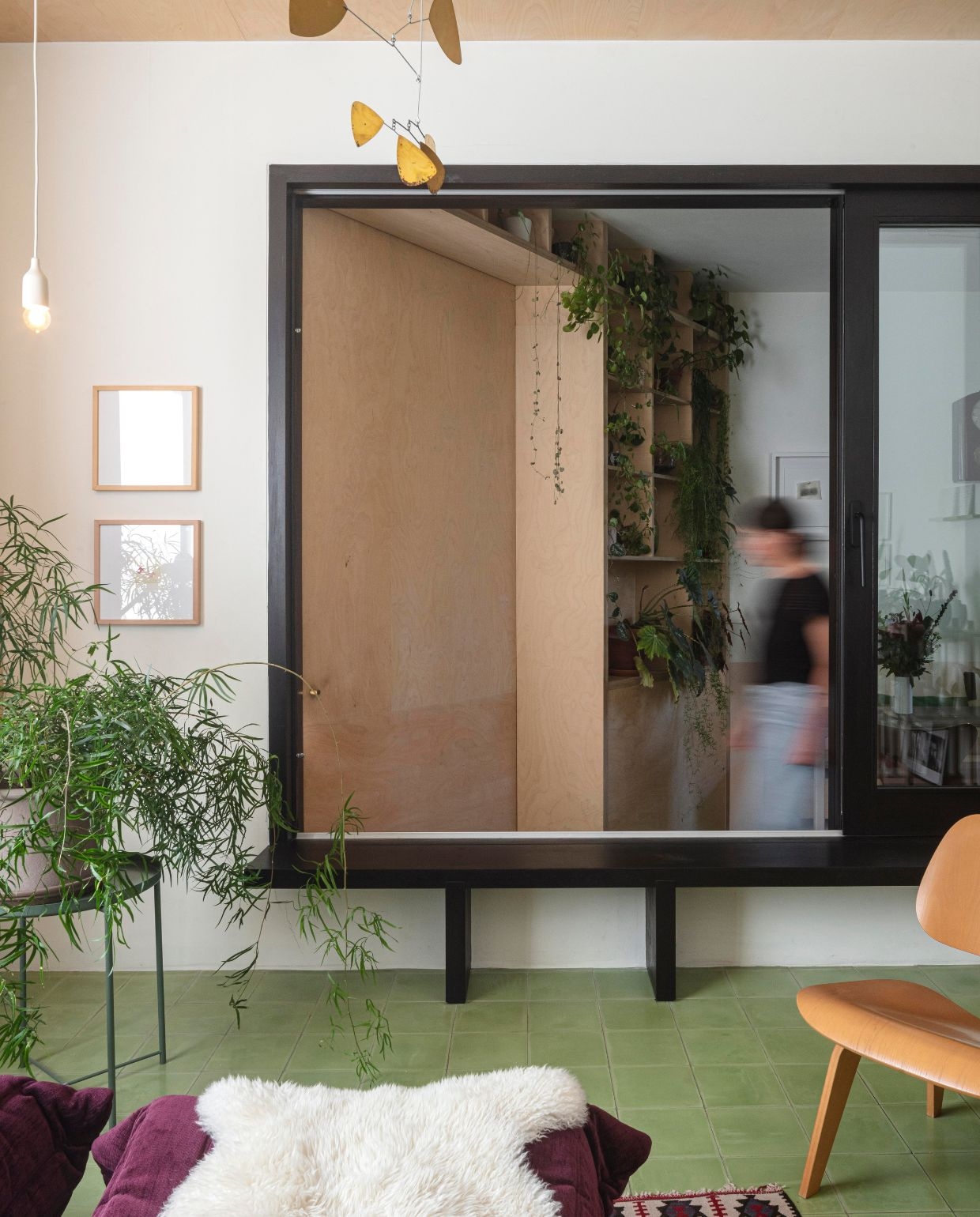 Groene cementtegels De Rocker Gent. Wandkleur Clunch van Farrow & Ball. Stoel Lcw Eames van Plywood Group. Poef Togo van Ligne Roset. Schapenvacht en bijzettafel Ikea. Lamp Jos Devriendt. Mobiel Lappalainen. vtwonen 03-2026 | fotografie Tim van de Velde