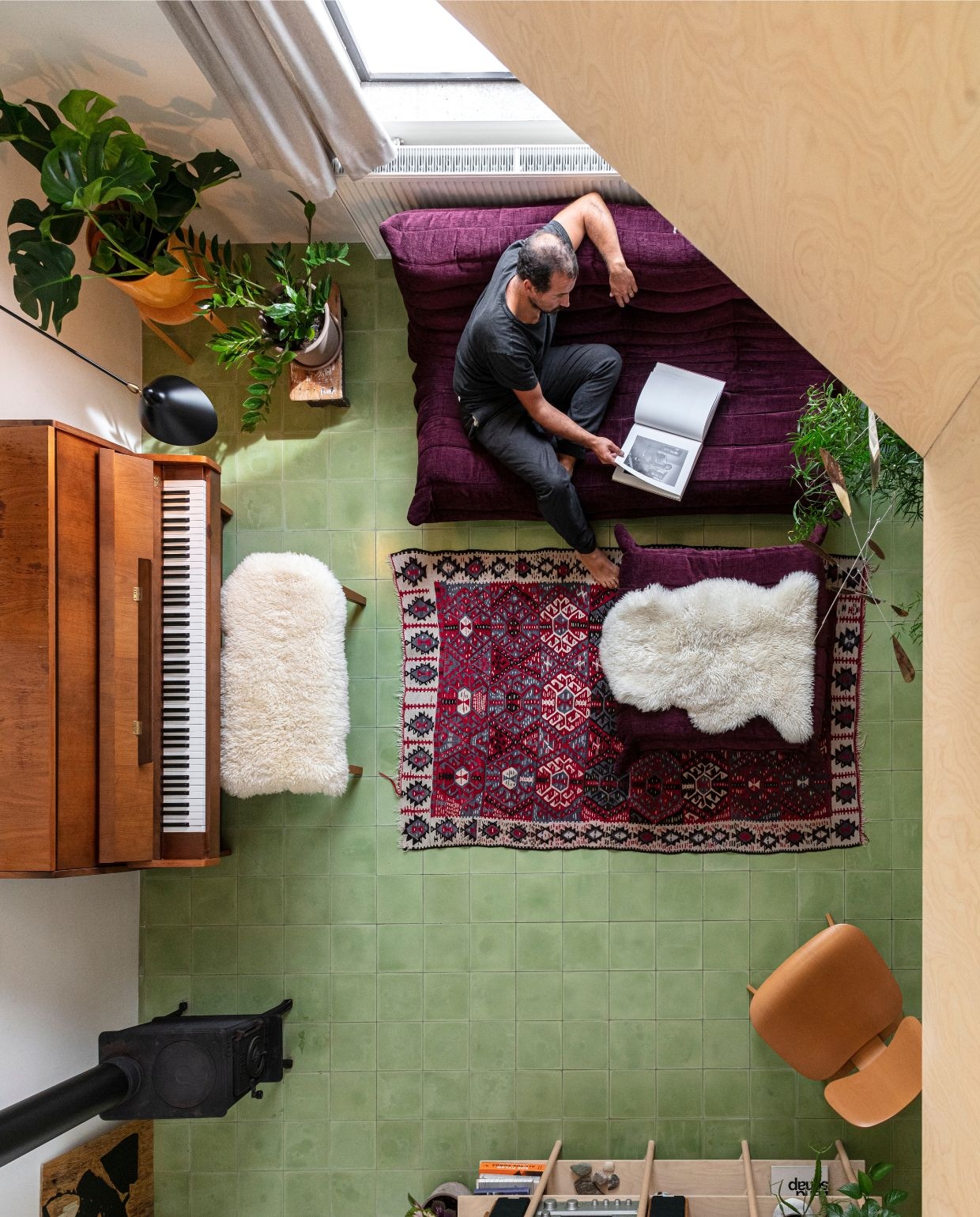 Groene cementtegels De Rocker Gent. Muurkleur Clunch van Farrow & Ball. Kachel F602 van Jøtul van de kringloop. Bank Togo van Ligne Roset. Piano Kawai. Schapenvachten en kruk Ikea. Pot Serax. Bijzettafel rommelmarkt. Wandmeubel 60 van Atelier Oh. Stoel Lcw Eames van Plywood Group. Wandlamp Applique 1 Zwart & Messing van Serge Mouille. Mobiel Lappalainen. Kunstwerk Malgorzata Maria Olchowska. Vloerkleed souvenir uit Marokko. vtwonen 03-2026 | fotografie Tim van de Velde