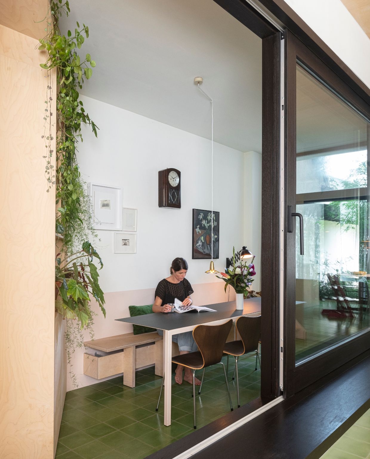 Groene cementtegels De Rocker Gent. Tafel Atelier Janda Vanderghote. Vlinderstoel Fritz Hansen Series 7 eikenfineer van Arne Jacobsen. Lamp Marguerite van Atelier Areti. Wandlamp en wandklok rommelmarkt. Stilleven Laurens Janda (Indra’s grootvader). vtwonen 03-2026 | fotografie Tim van de Velde