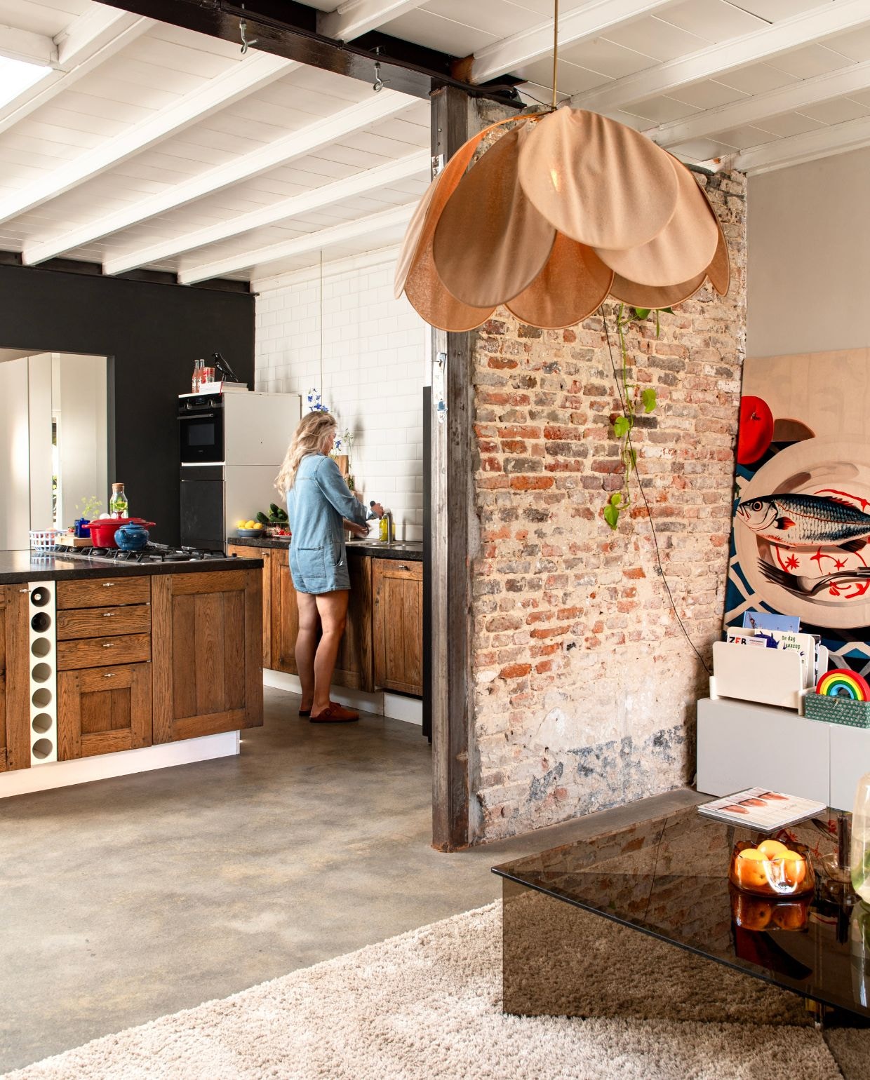 Keuken met Belgisch hardstenen werkblad en ovens van Gaggenau via Marktplaats. Theepot Le Creuset. Rode pan Lidl. Blauwe fruitschaal Hema. Plafondlamp Georges Store. Kunstwerk is een kleed bevestigd op hout. vtwonen 03-2026 | fotografie Caroline Coehorst