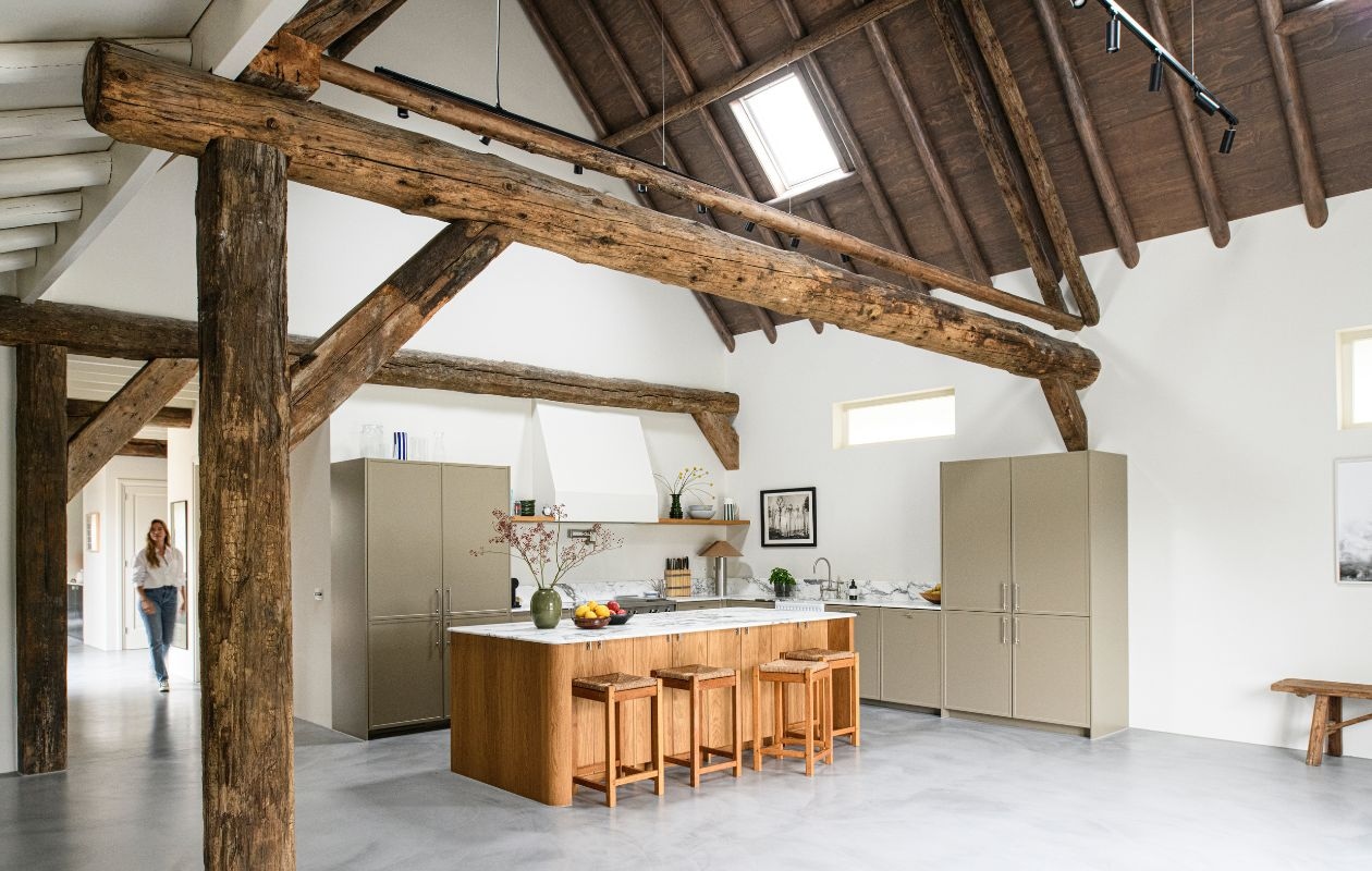 Keukenkasten en eiland op maat gemaakt. Werkblad Arabescato marmer van Stone Creation. Spoelbak Devol Kitchens. Kraan, pot filler Studio Ore. Fornuis Bertazzoni. Greepjes Meraki. Vaas op werkblad Arket. Stalen lamp Zara Home. Krukken vintage. Muurverf School House White van Farrow & Ball. vtwonen 04-2026 | styling Esther Loonstijn | fotografie Louis Lemaire