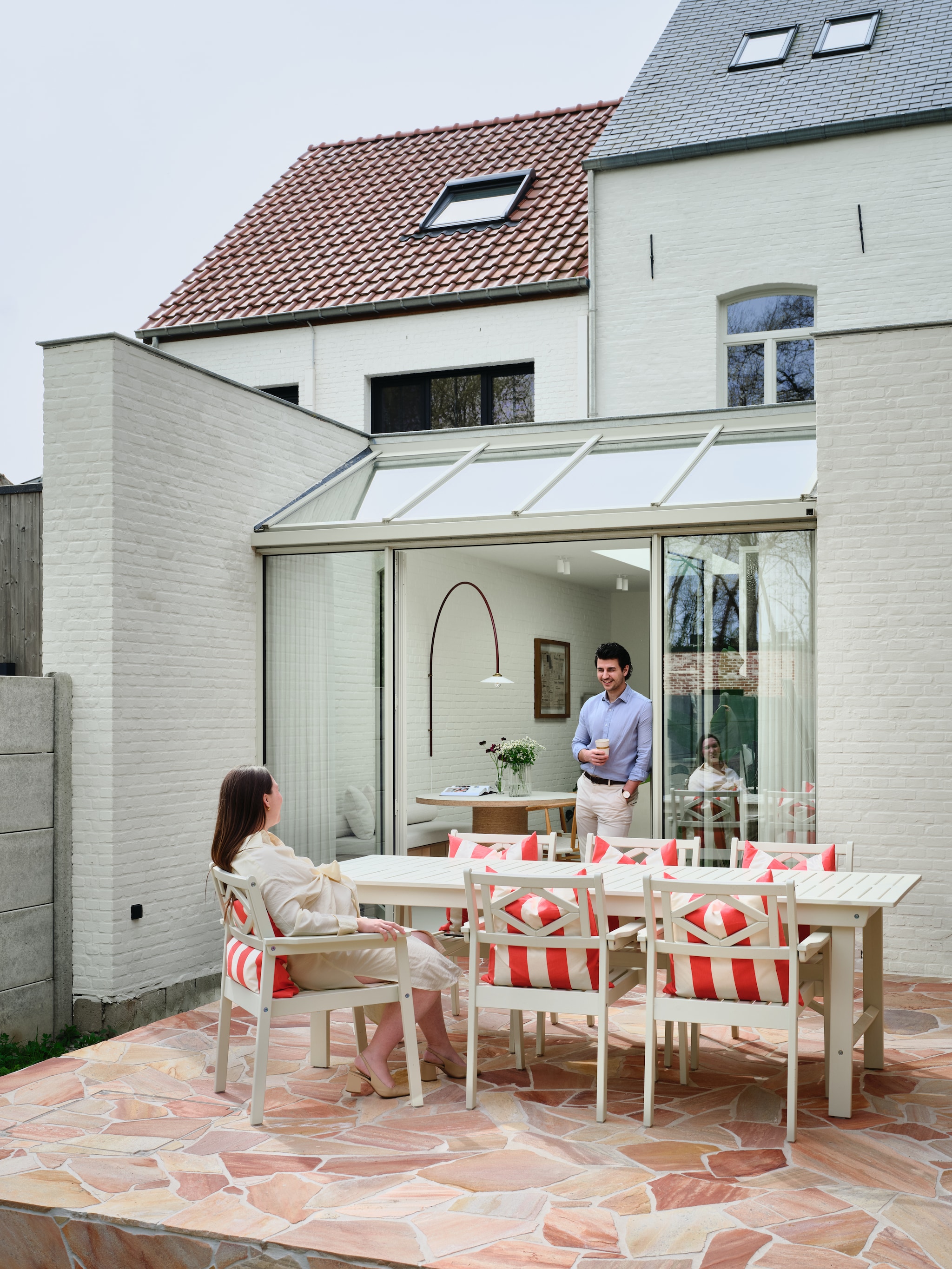 Vloer Flagstone Romano Rosé van Hb-classics. Tafel en stoelen Ikea. Kussens H&m Home. Lamp Muller Van Severen. Afwerking gevel Kalei in Ivory van Stoopen & Meeus, met extra witpigment. Kleur serre Ral 7032. vtwonen 07-2026 | fotografie Mr. Frank