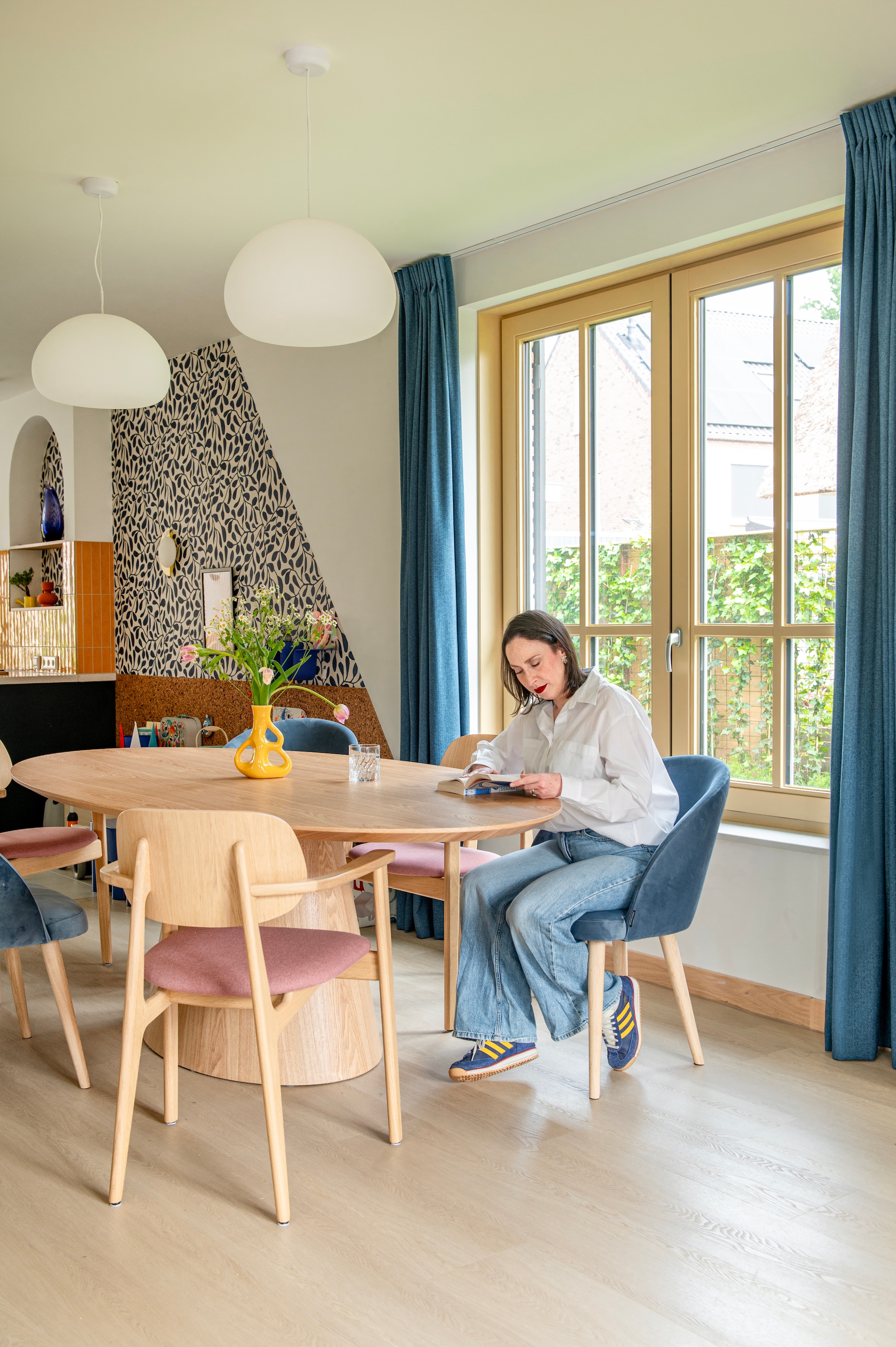 Muurkleur Wevet van Farrow & Ball. Behang Twist van Eijffinger. Tegels Luz Giallo van Marazzi. Gordijnen De Ploeg. Lampen Muuto. Roze stoelen Sav & Økse. Blauwe stoelen Sofacompany. Vaas Three Ears van Polspotten.