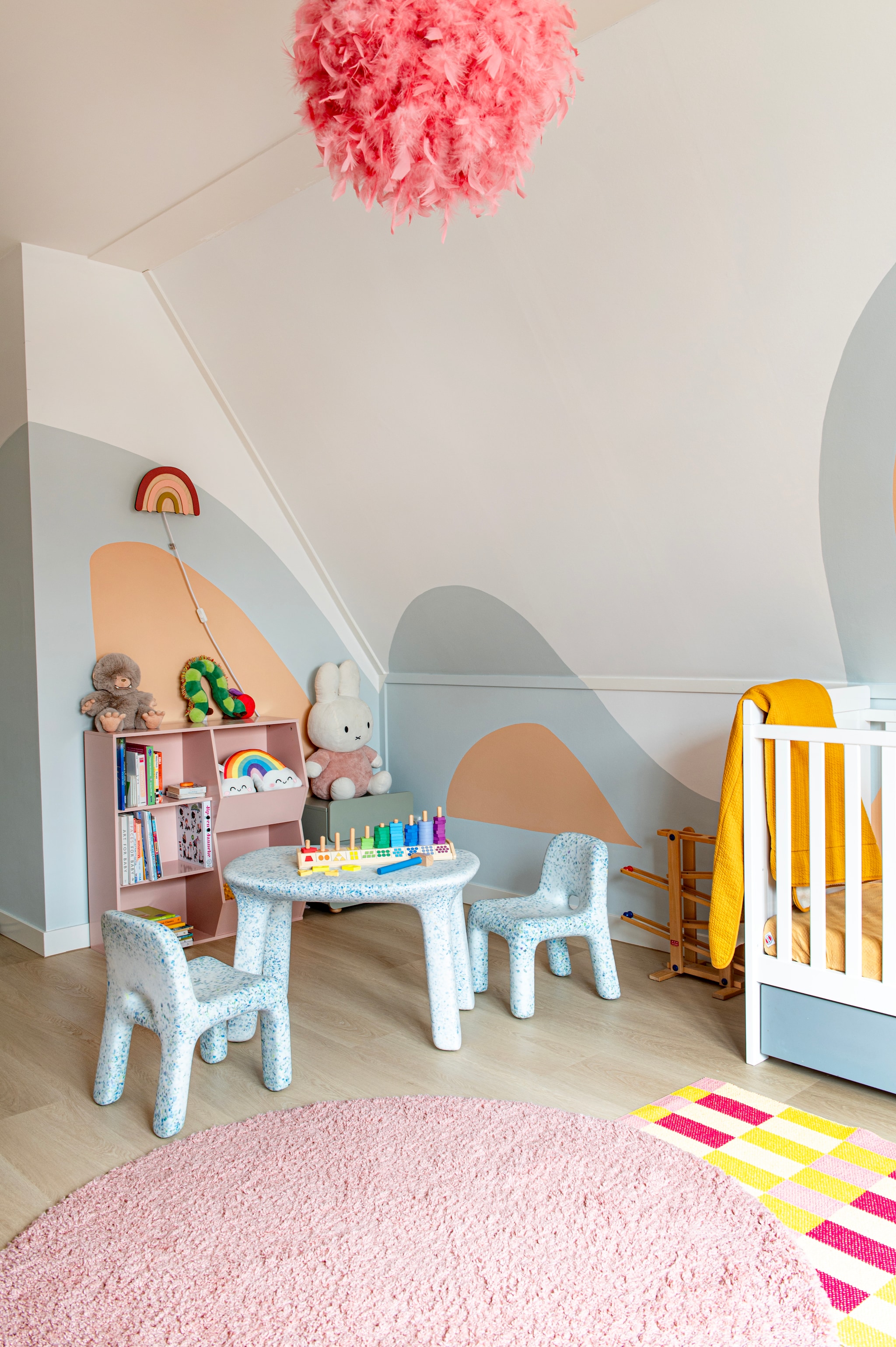 Tafel Luisa en stoelen Charlie van Ecobirdy. Onderste kleed Favola en bovenste kleed Comfy van Rugvista. Nachtkastje Nous Kids. Hanglamp Drava van Beliani. Boekenkast Tobias van Sweeek. Wandlamp Regenboog van Verslingerd aan Hout. Muurkleur wit All White van Farrow & Ball. vtwonen 07-2026 | fotografie Caroline Coehorst