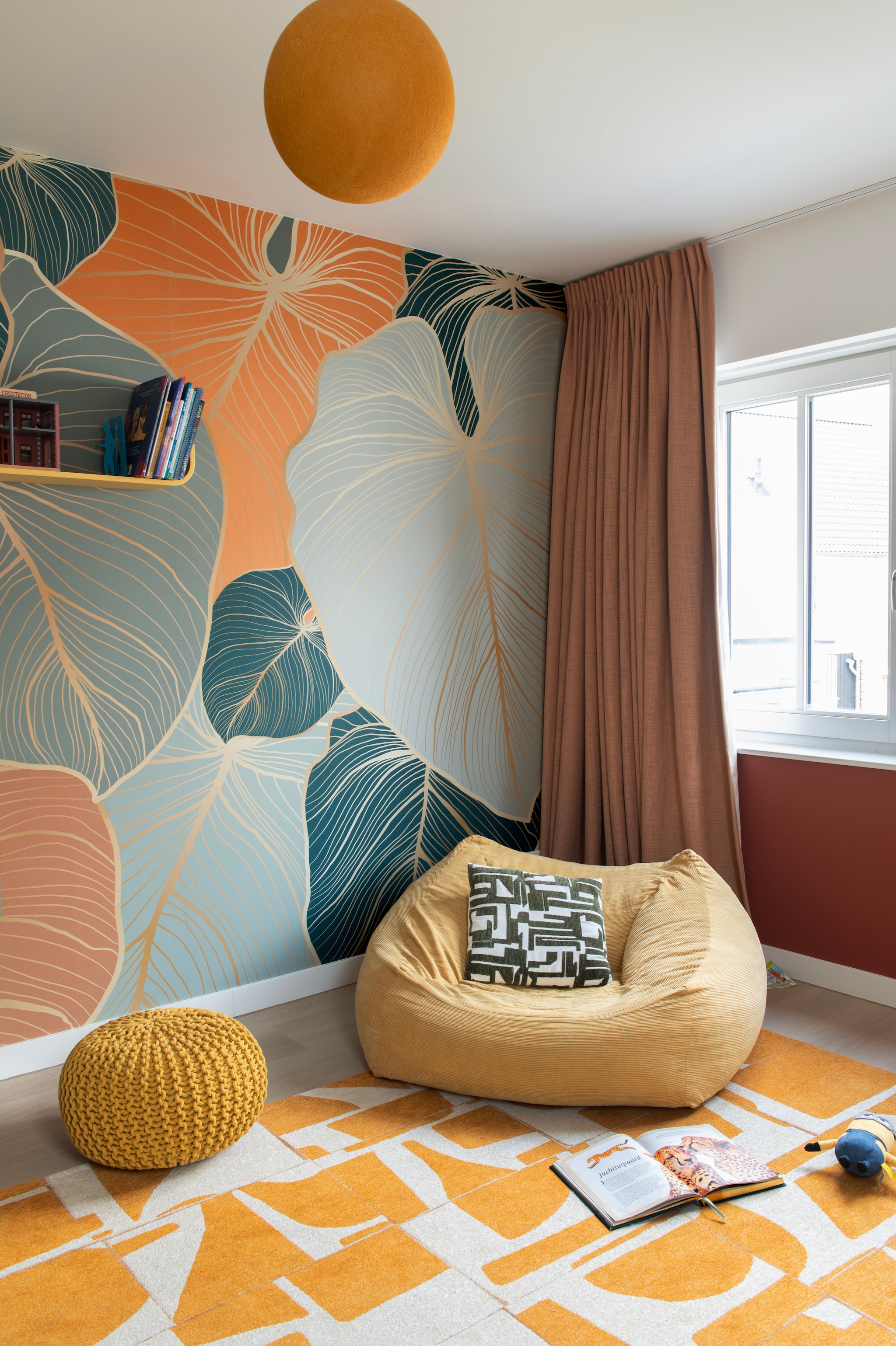 Behang bladeren met koper van Fotobehang.com. Gordijnen Beyond van Vadain. Vloerkleed Papercut Curry van Louis De Poortere via Westwing. Poef Bisho van La Redoute. Wandplank Flower van Tenzo. Lamp Cotton Ball Lights. Kussen Fran van Westwing. vtwonen 07-2026 | fotografie Caroline Coehorst